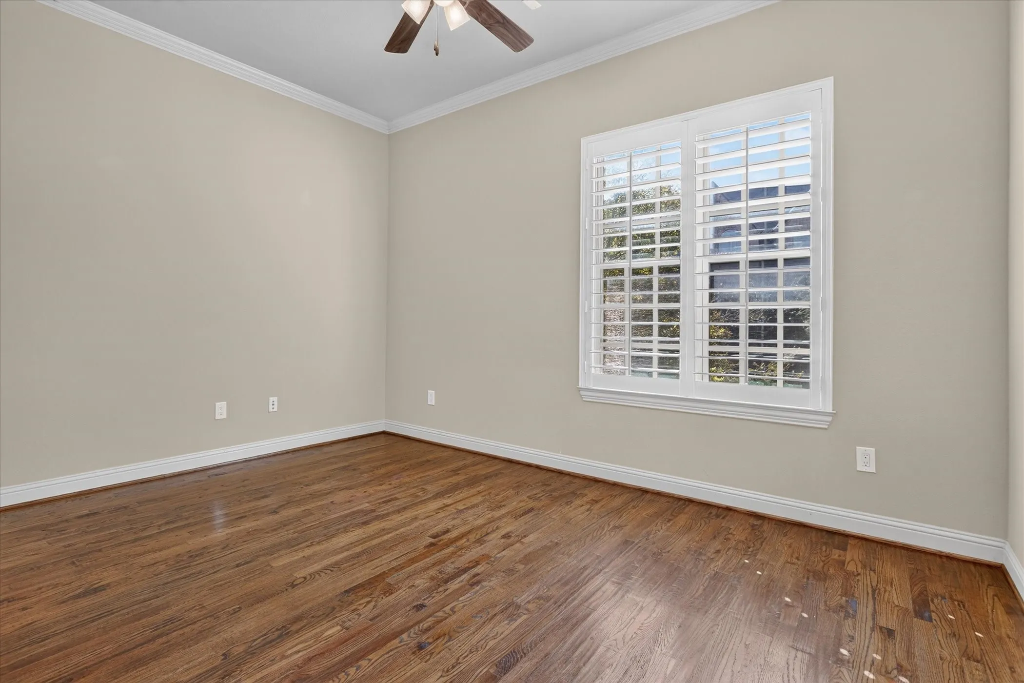 Bedroom 2 on main level, 2nd floor, with hand scrapped hard wood flooring, crown molding, white plantation shutters, and a ceiling fan with integrated lighting