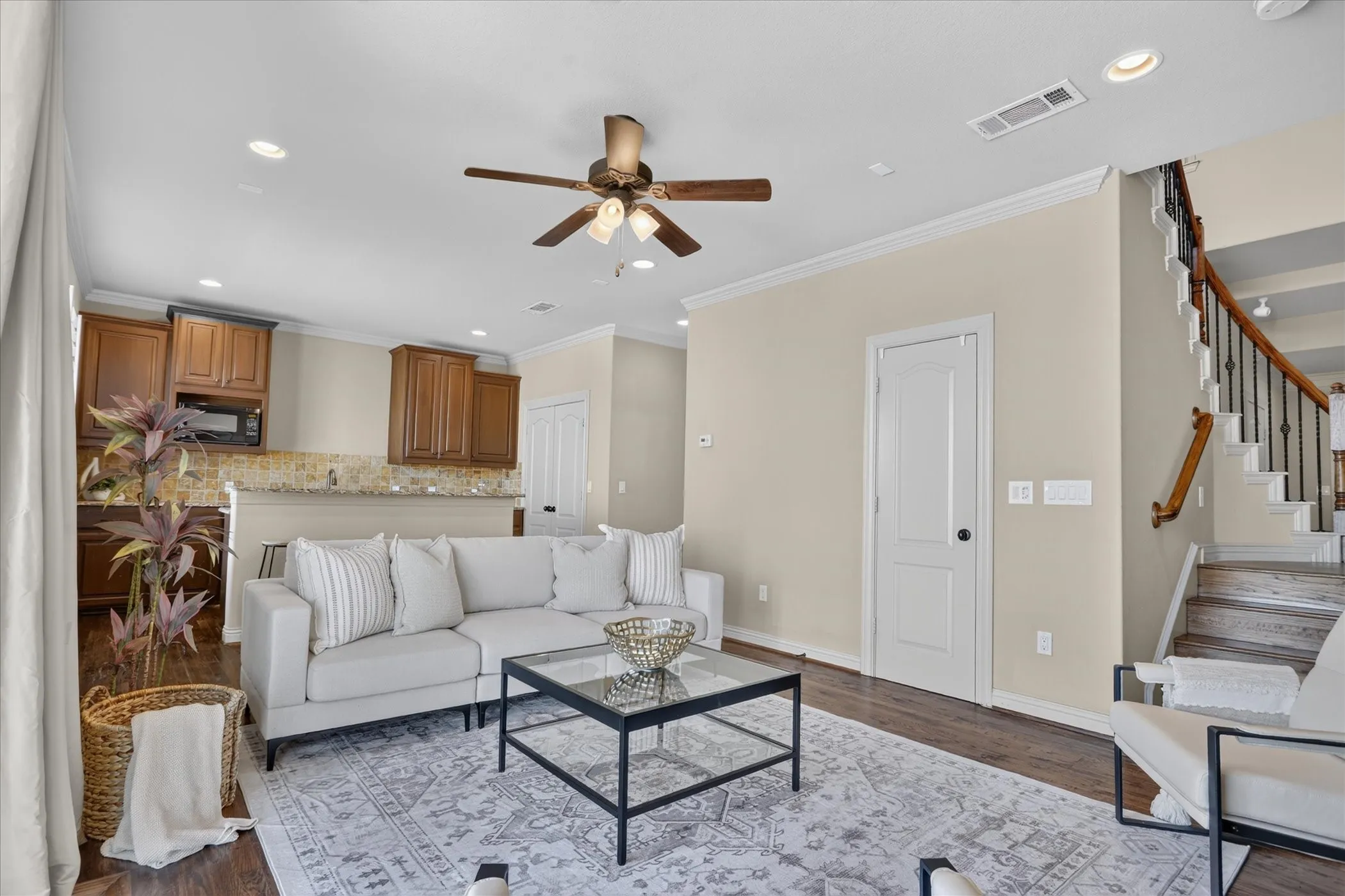 Flex space featuring handscraped hardwood flooring, full bath, two large walk in closets, laundry room, and a large wet-bar with cabinets, mini sink and mini-fridge. Sliding glass door leads to balcony with winding staircase down to covered patio.