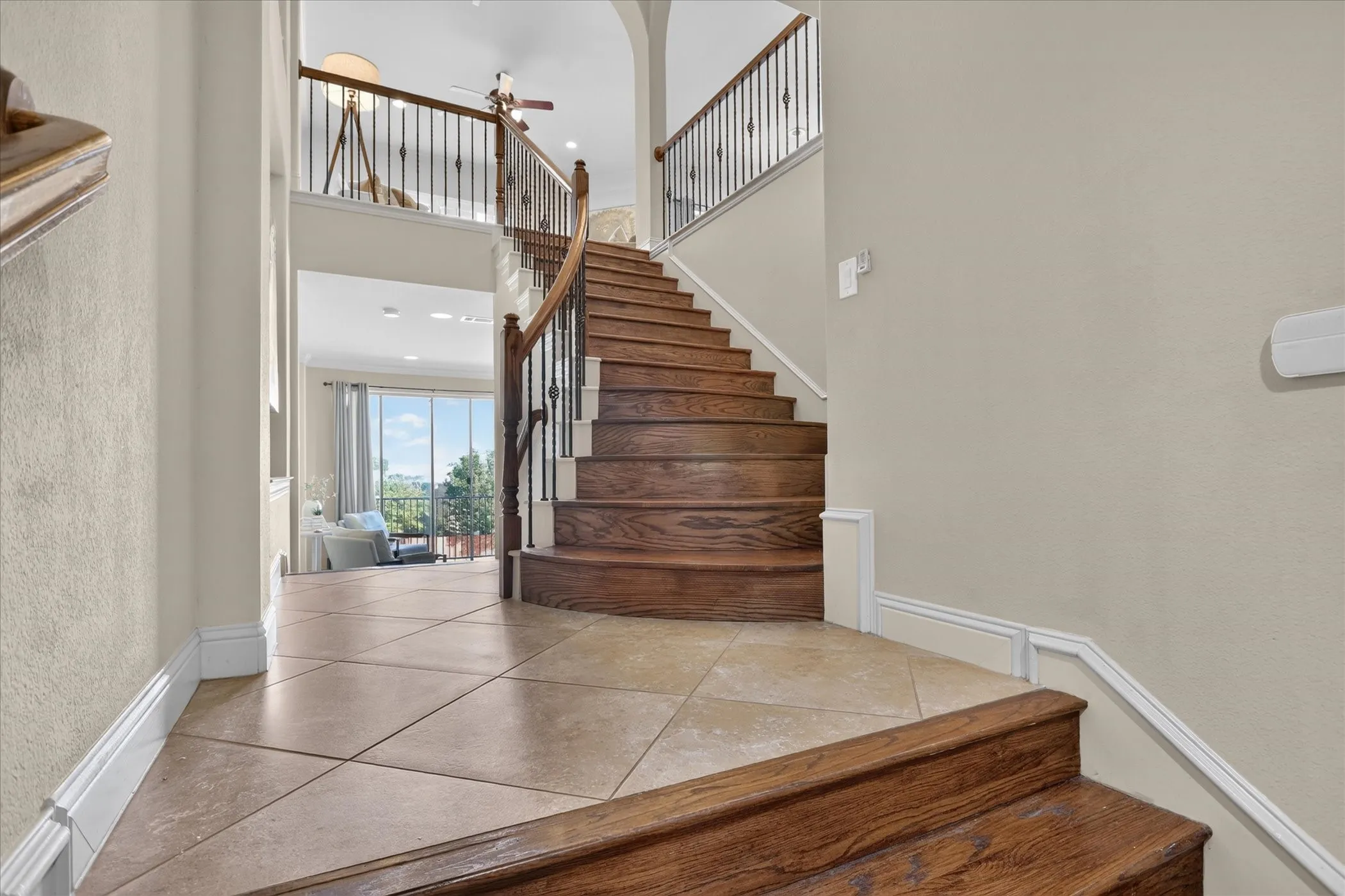 Grand entryway featuring stone tile flooring, a curved staircase with stained wood treads, and metal balusters