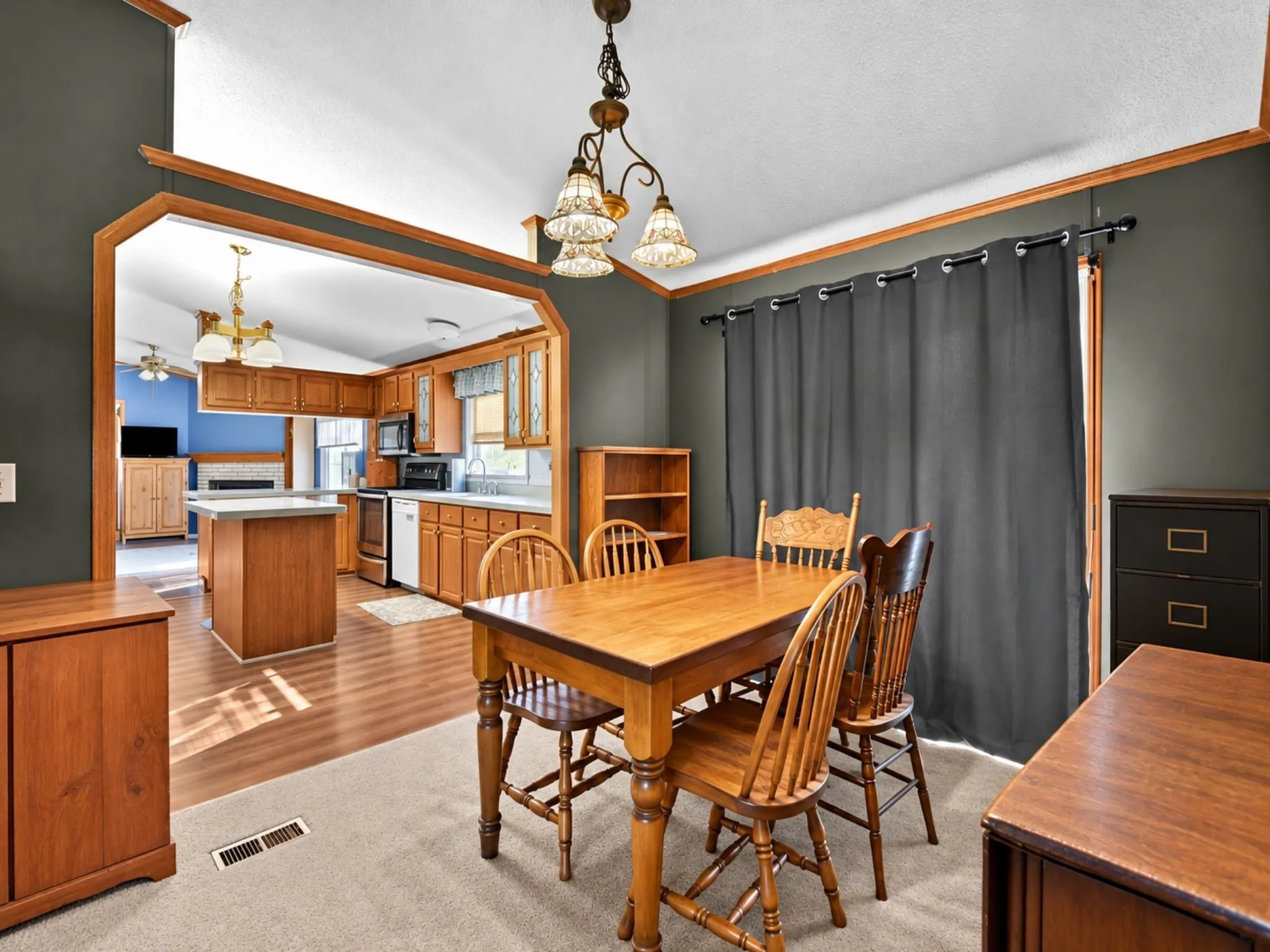 Dining area featuring a three-light decorative chandelier, wood-finish flooring, and large pass-through opening