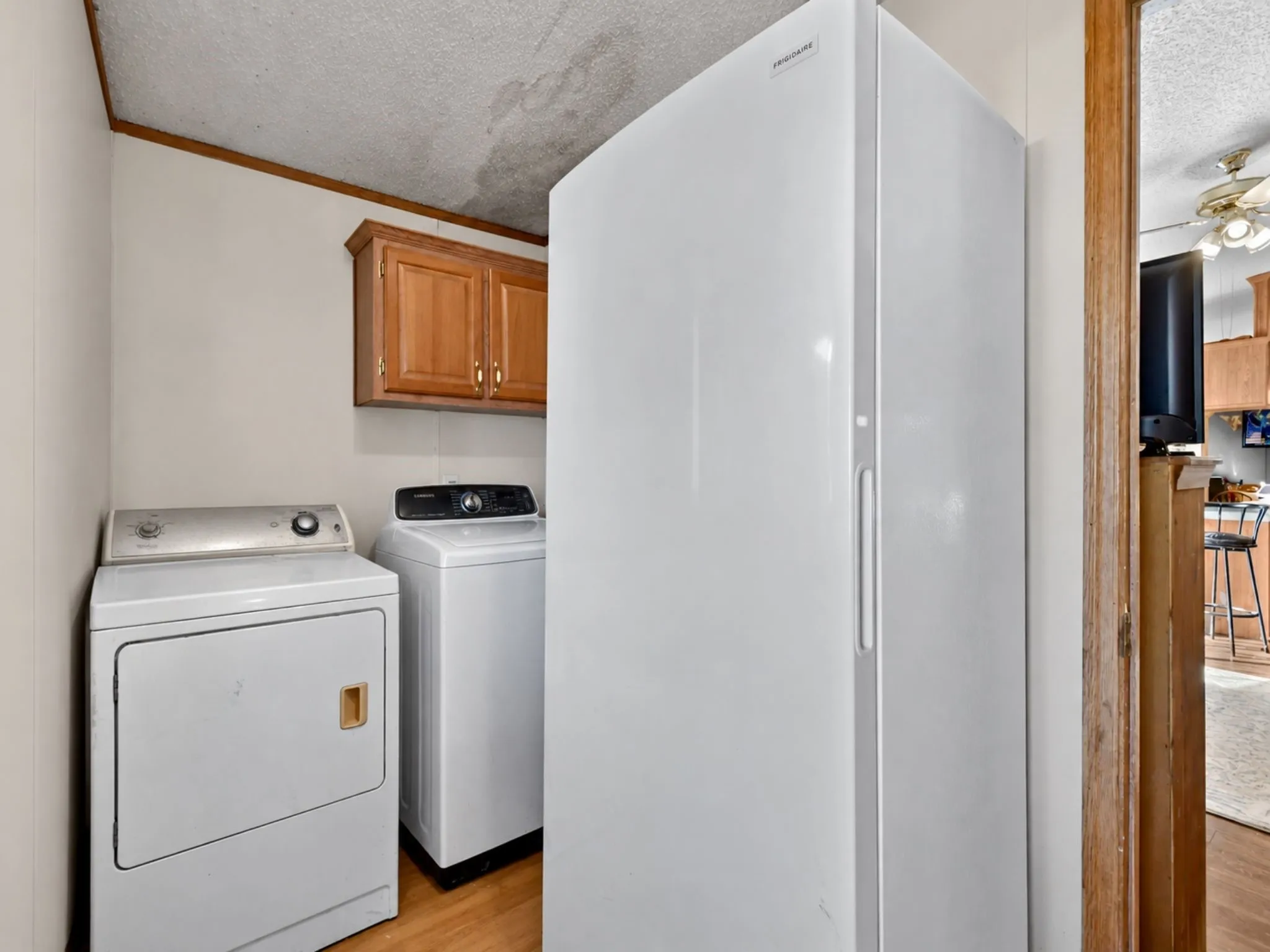 Utility space featuring wood-finish flooring, wall-mounted wood cabinetry, and a full-size upright freezer