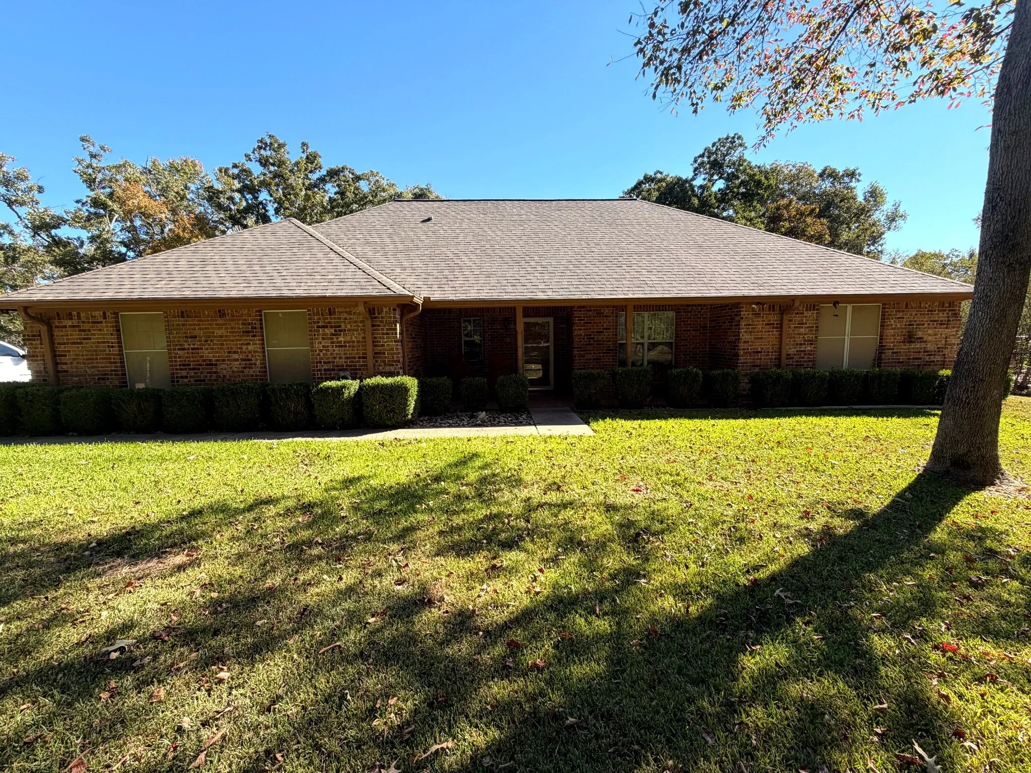 Single-story brick exterior featuring a hip roof, covered entryway, and manicured landscaping