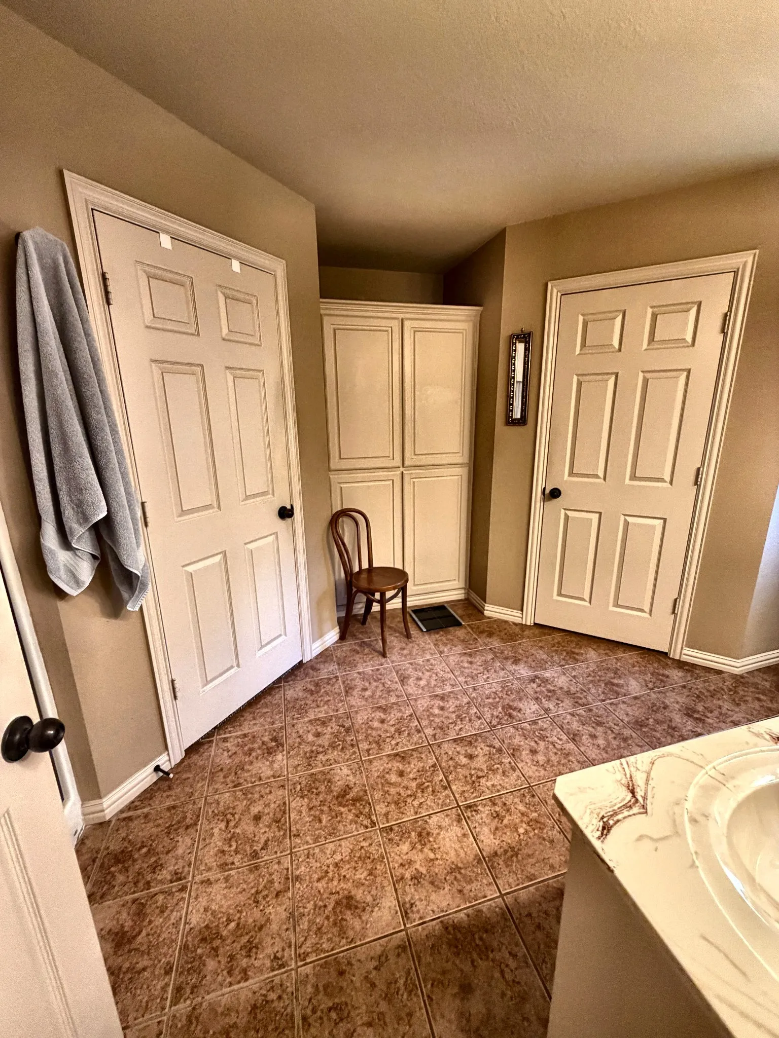 Tile flooring arranged in a diagonal pattern, white six-panel doors, and built-in floor-to-ceiling cabinetry with shaker-style panels