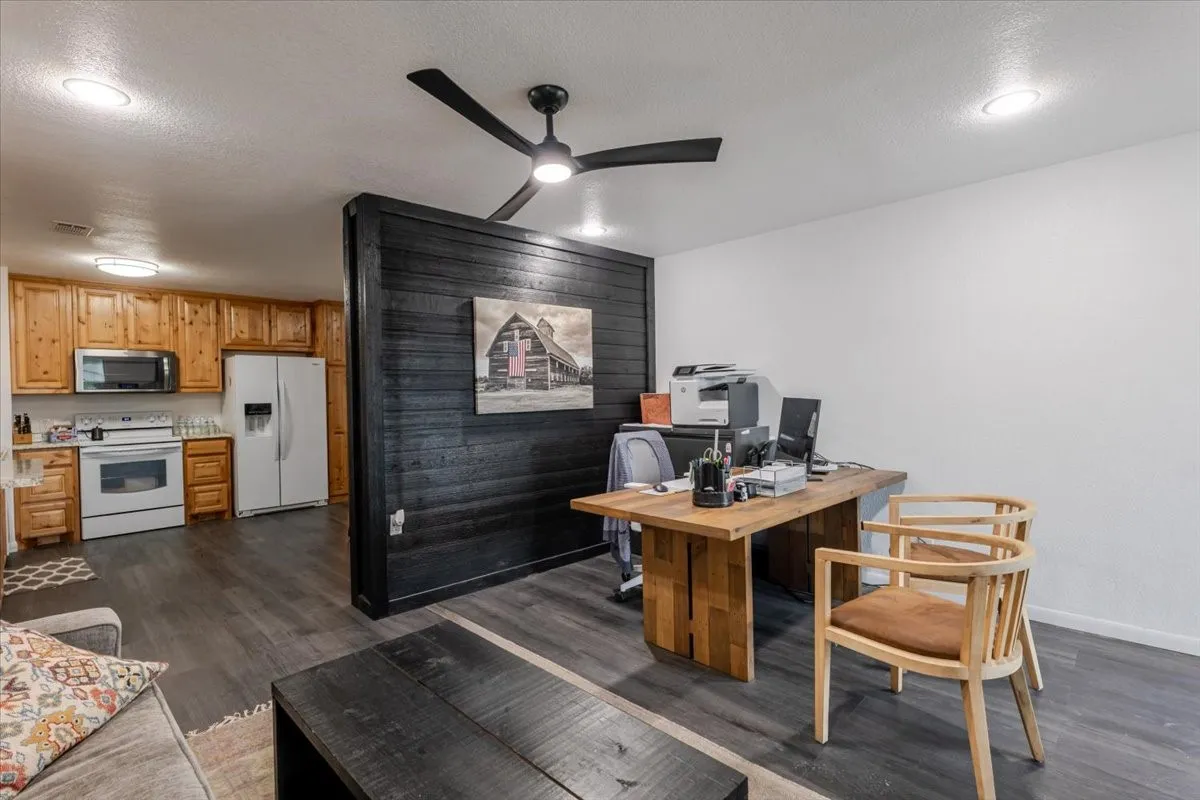 Reception area Open-concept space featuring wood-finish flooring, a matte black horizontal plank accent wall, recessed lighting, and a modern ceiling fan