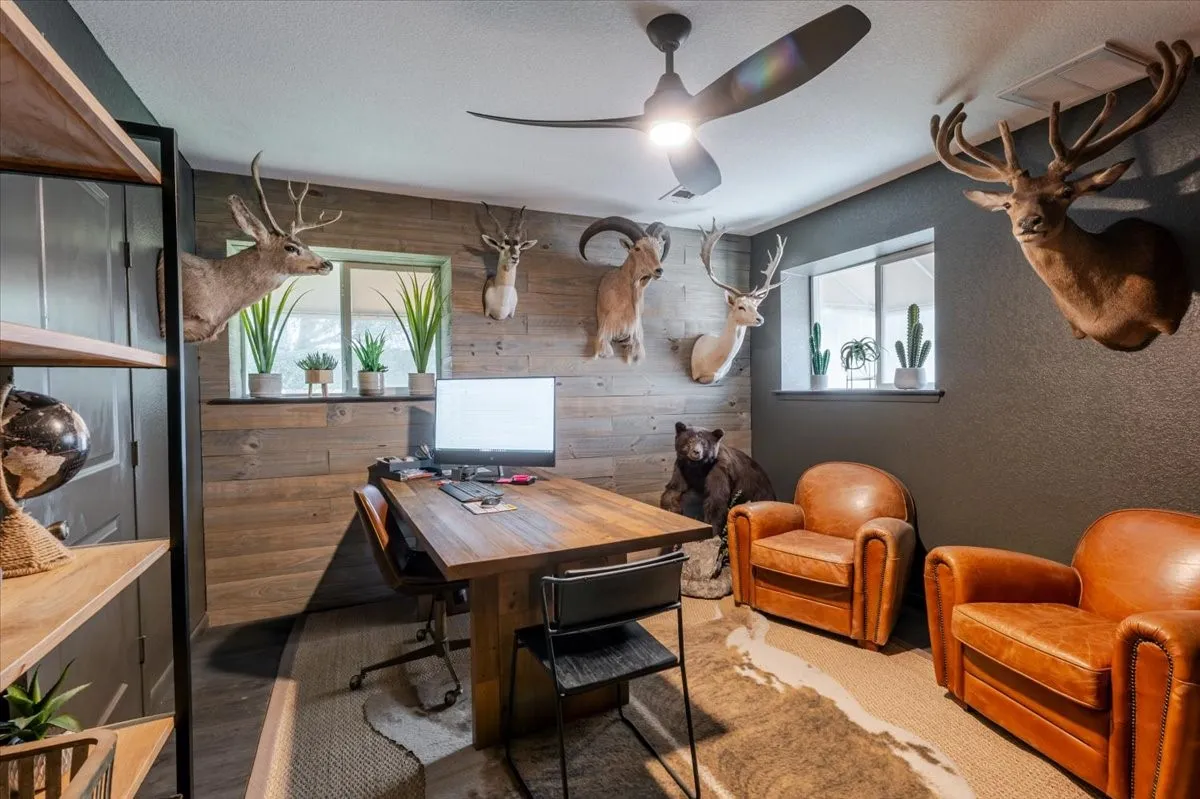 Room featuring horizontal wood-plank wall cladding, dual windows, and a three-blade modern ceiling fan