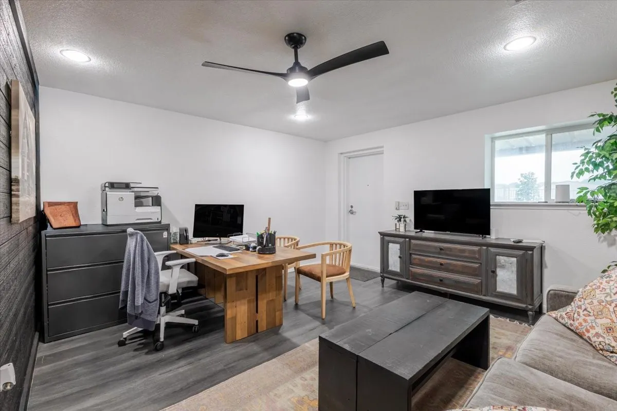 Room featuring wood-finish flooring, a dark-toned wood-plank accent wall, recessed lighting, and a modern ceiling fan