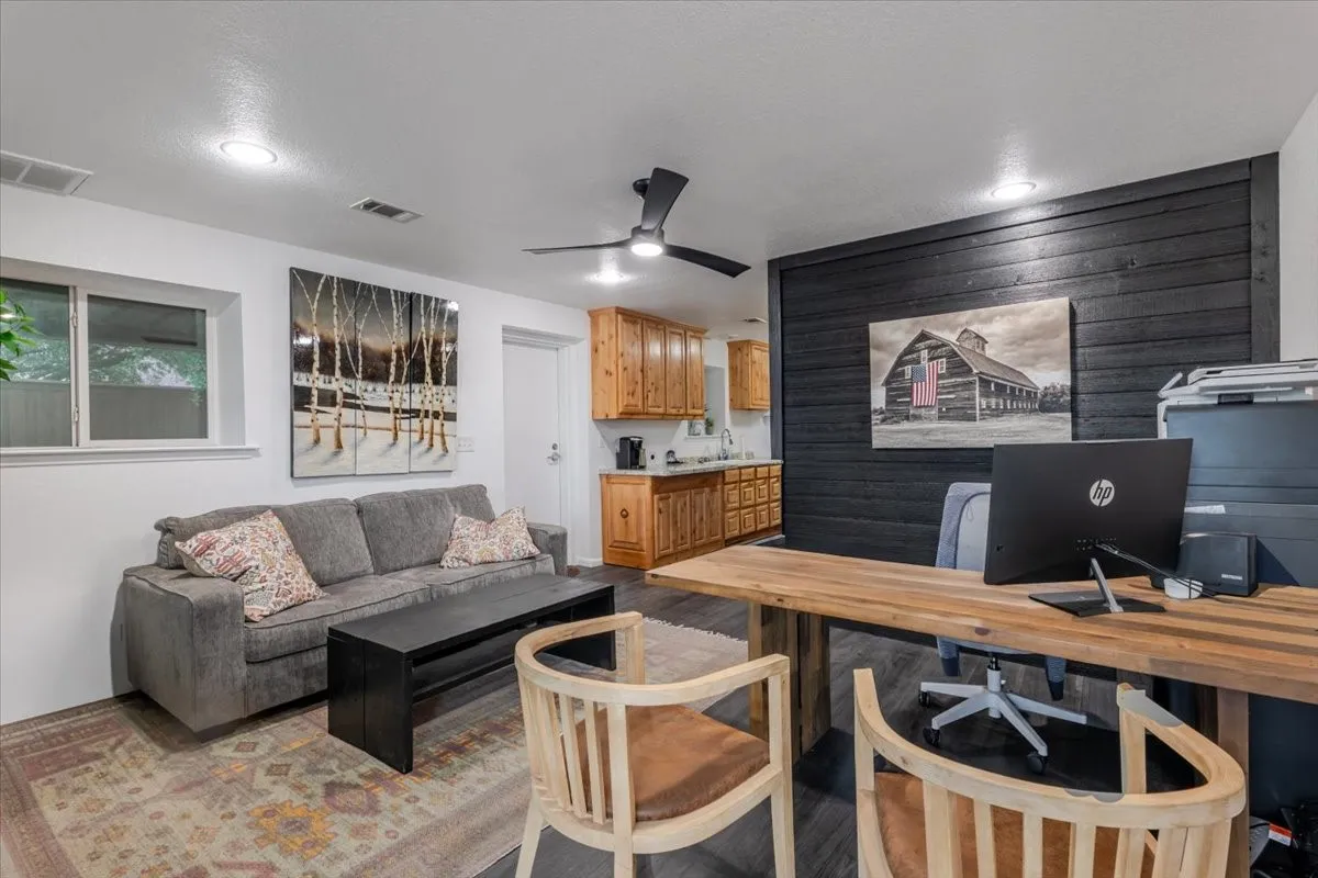 Reception area with black horizontal wood-plank accent wall, wood cabinetry with integrated sink, recessed lighting, and ceiling fan