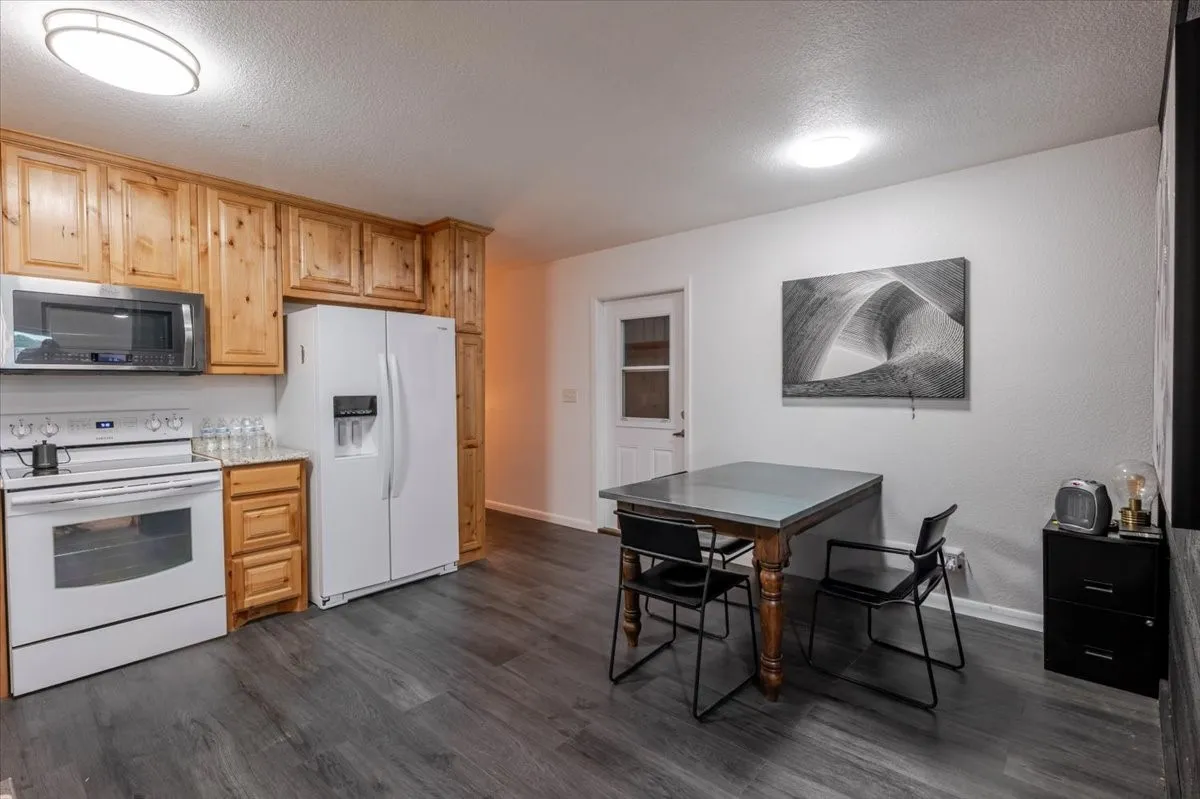 Breakroom featuring wood-finish cabinetry, stone-style countertops, stainless steel microwave, and wood-finish flooring