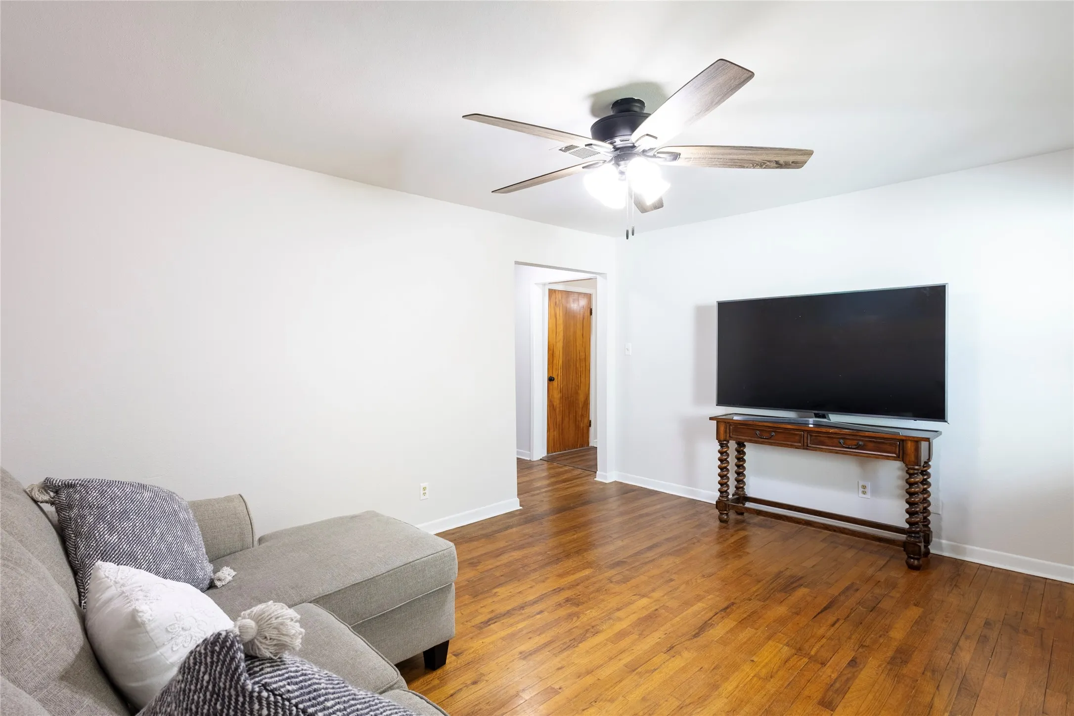 Wood-finish flooring, ceiling fan with integrated light fixture, and solid wood interior door
