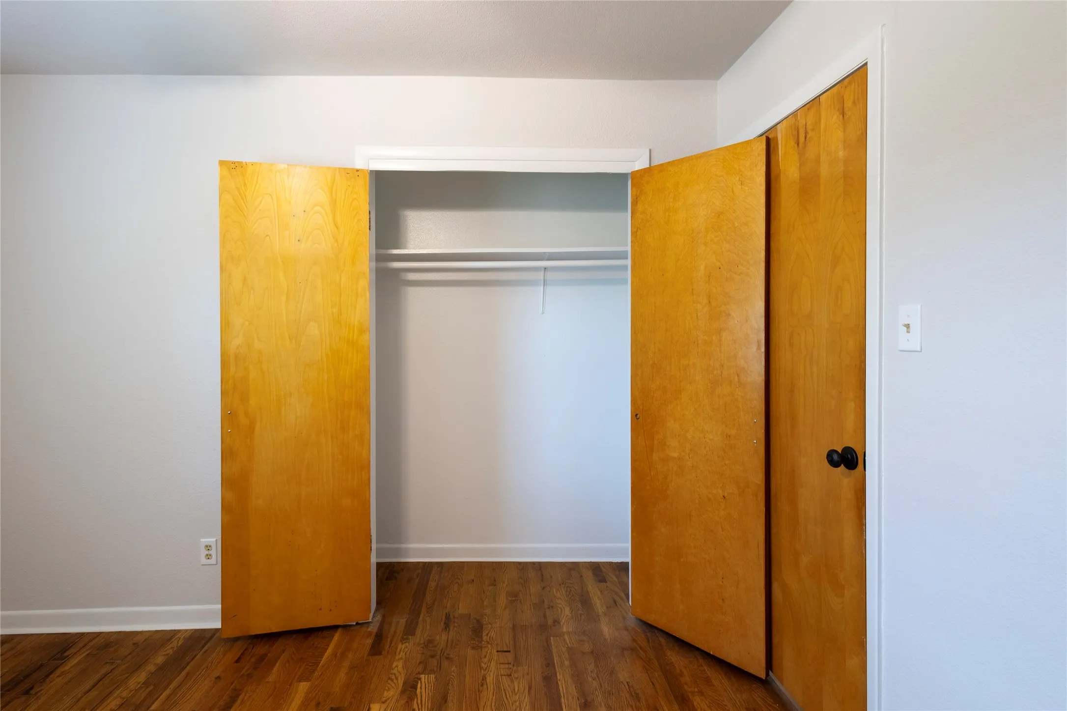 Wood-finish flooring, full-height wooden swinging closet doors, and built-in closet shelving