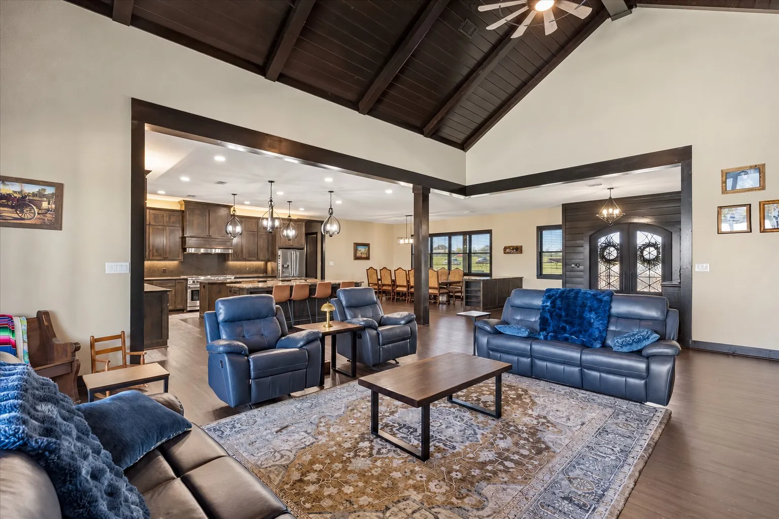 Vaulted ceilings with exposed dark wood beams, wood-finish flooring, recessed lighting, and expansive open-concept layout