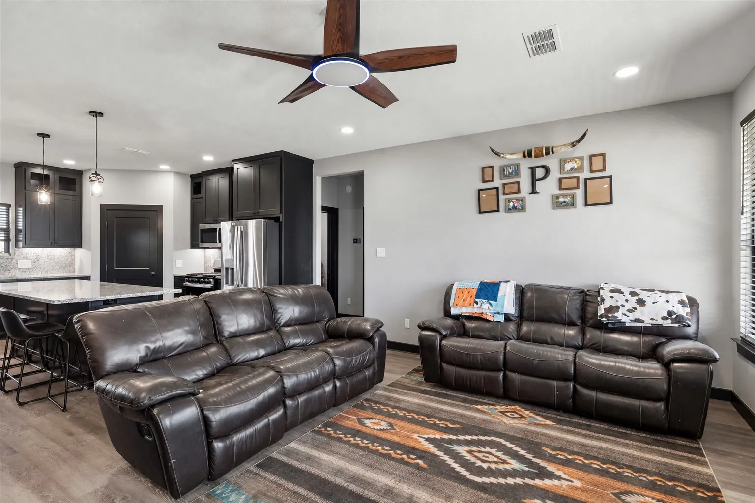 Kitchen featuring dark cabinetry, stone-finish countertops, stainless steel appliances, recessed lighting, and a modern ceiling fan
