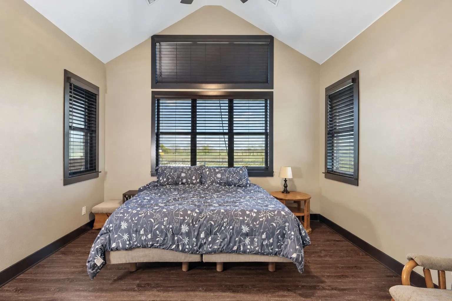 Vaulted ceiling, wood-finish flooring, and expansive windows with dark-framed trim