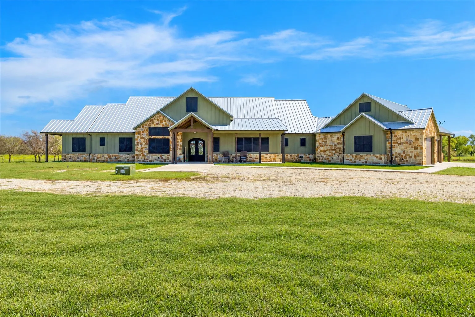 Custom exterior featuring stone masonry, board-and-batten siding, a metal roof, and a covered front entryway with timber supports