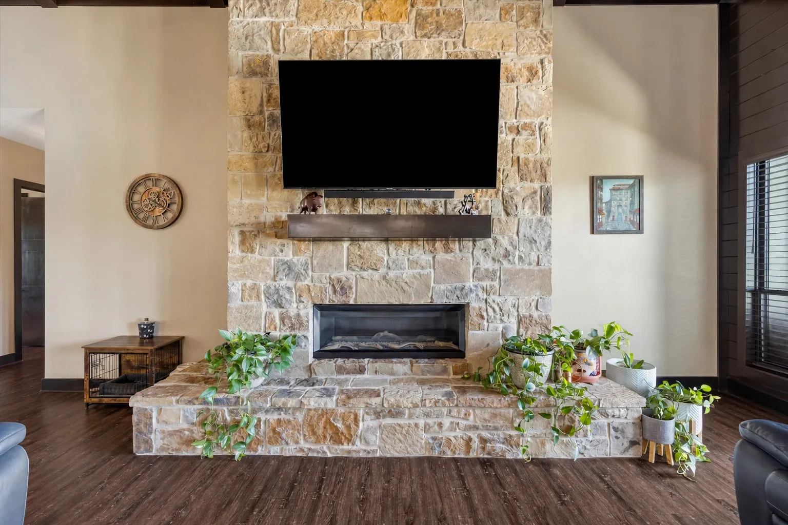 Floor-to-ceiling natural stone fireplace with a raised hearth, linear insert, and dark wood-finish beam mantel