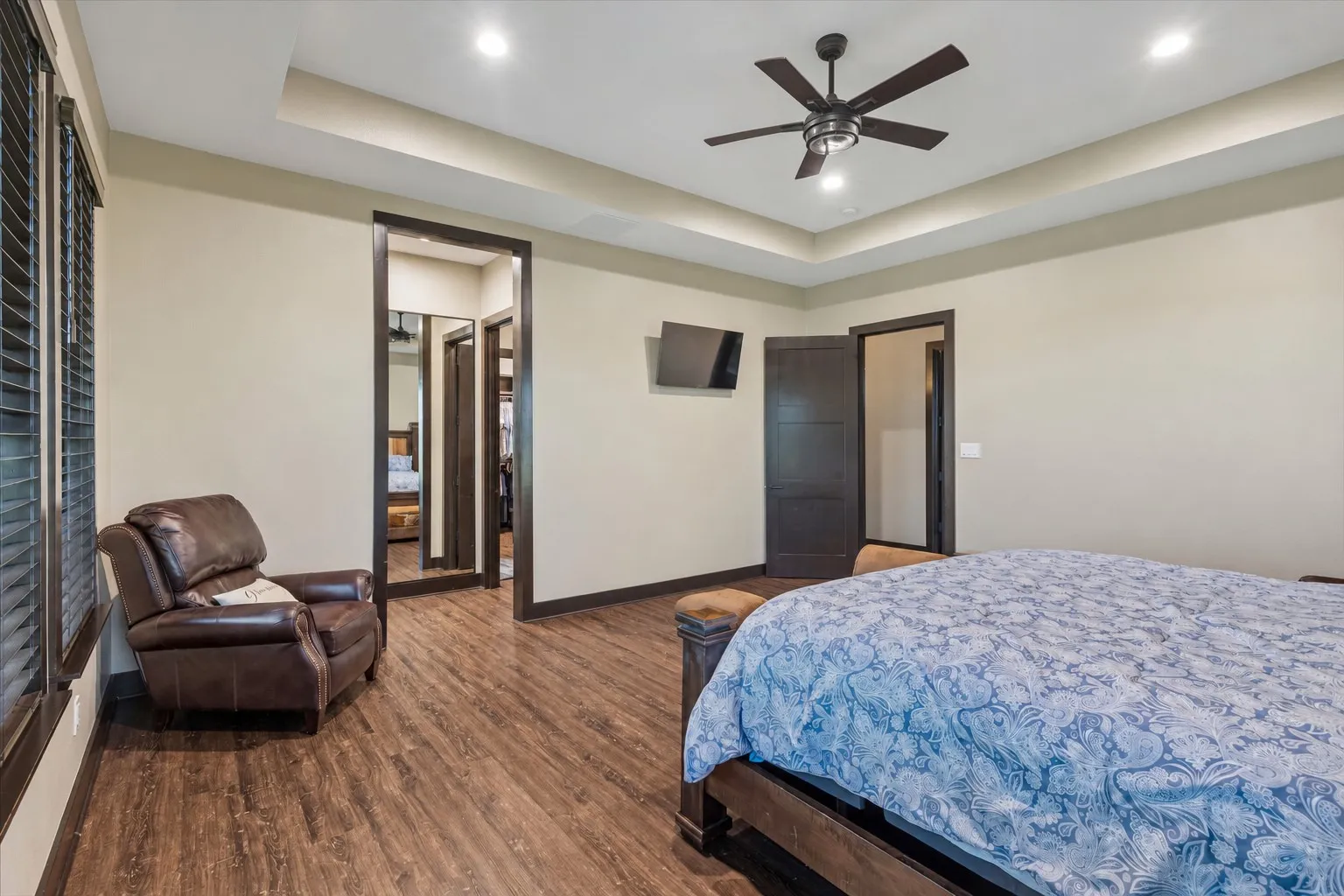 Room featuring wood-finish flooring, tray ceiling, recessed lighting, and a ceiling fan with integrated lighting
