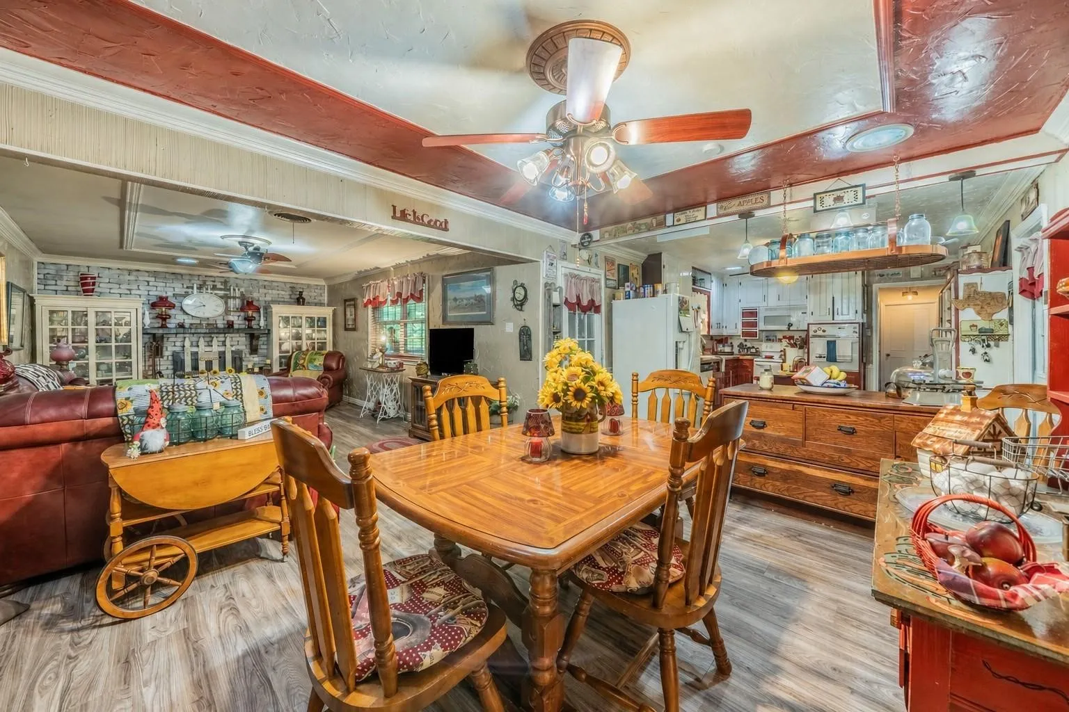Open-concept interior featuring wood-finish flooring, a recessed ceiling with decorative wood-toned trim, and a multi-light ceiling fan