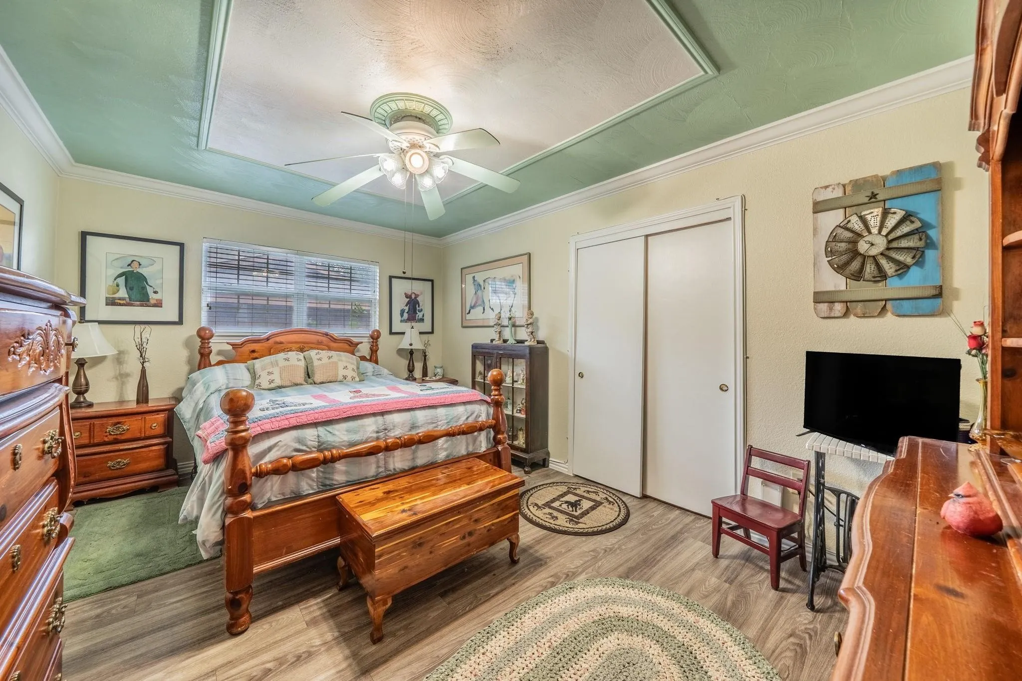 Wood-finish flooring, ceiling fan with integrated lighting, dual-panel closet doors, and recessed ceiling detail