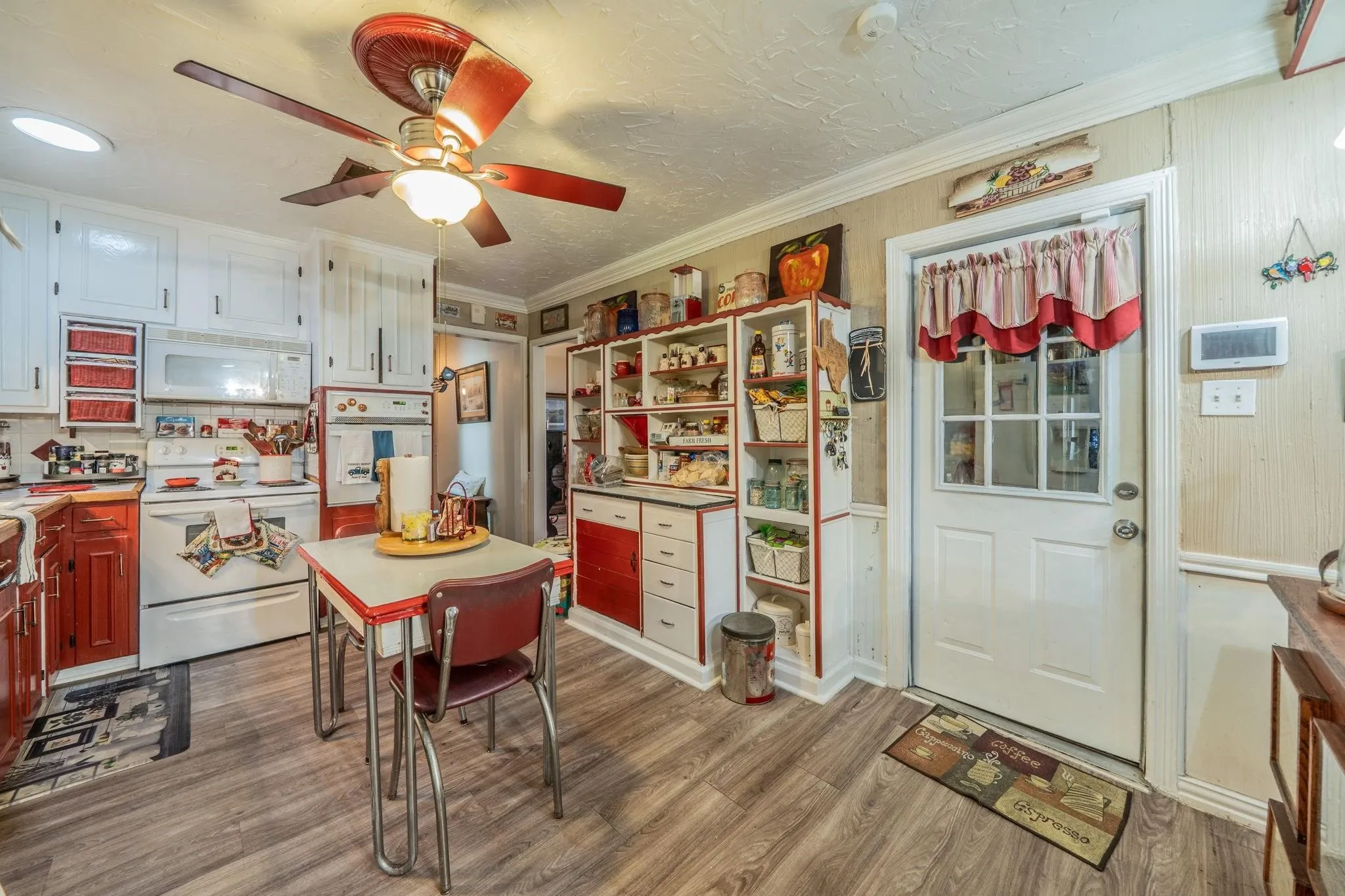 Kitchen featuring wood-finish flooring, white cabinetry, built-in wall shelving, integrated oven, and a six-pane glass entry door