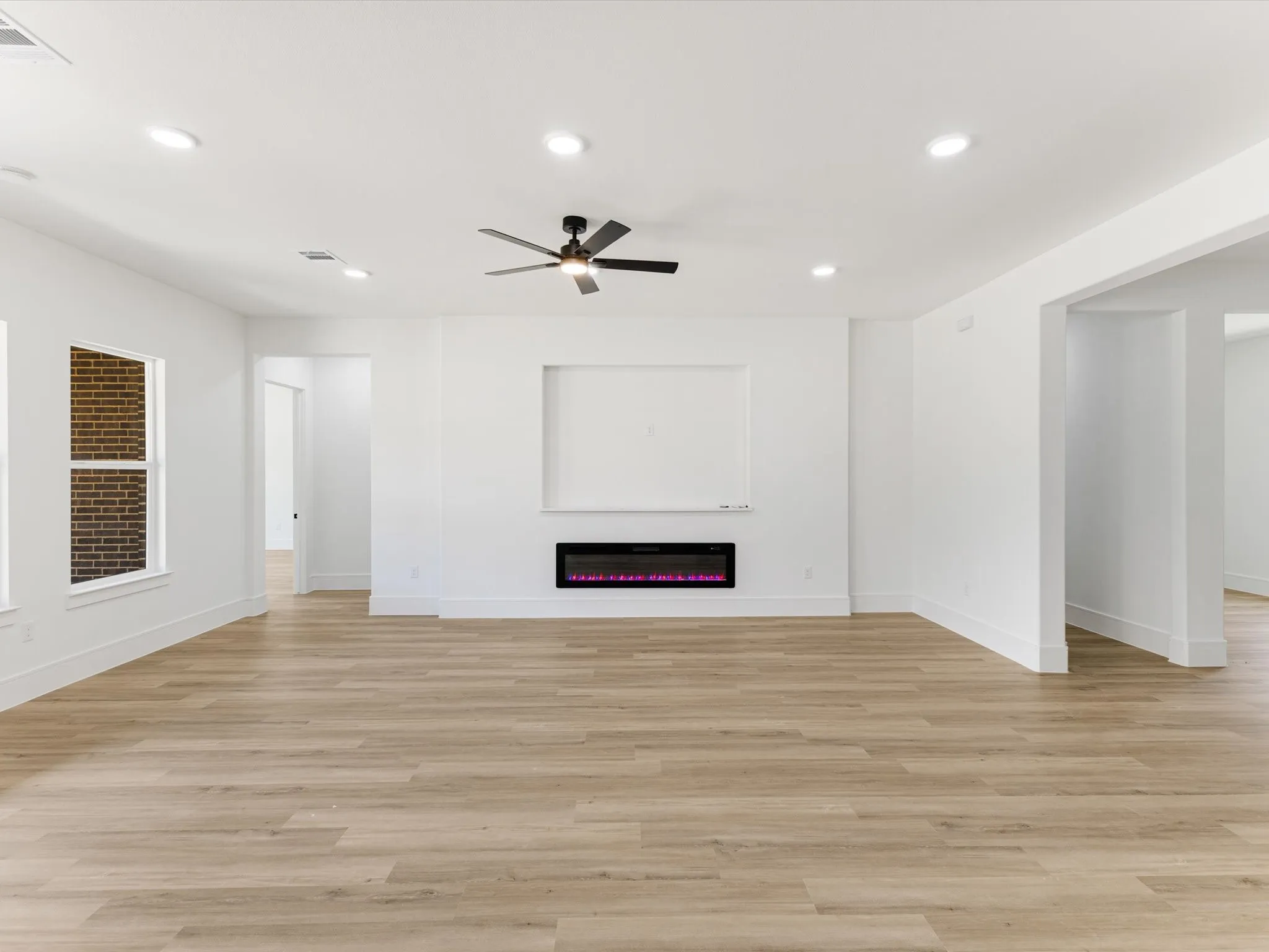 Interior featuring wood-finish flooring, recessed lighting, a ceiling fan, a built-in electric fireplace, and a recessed wall niche