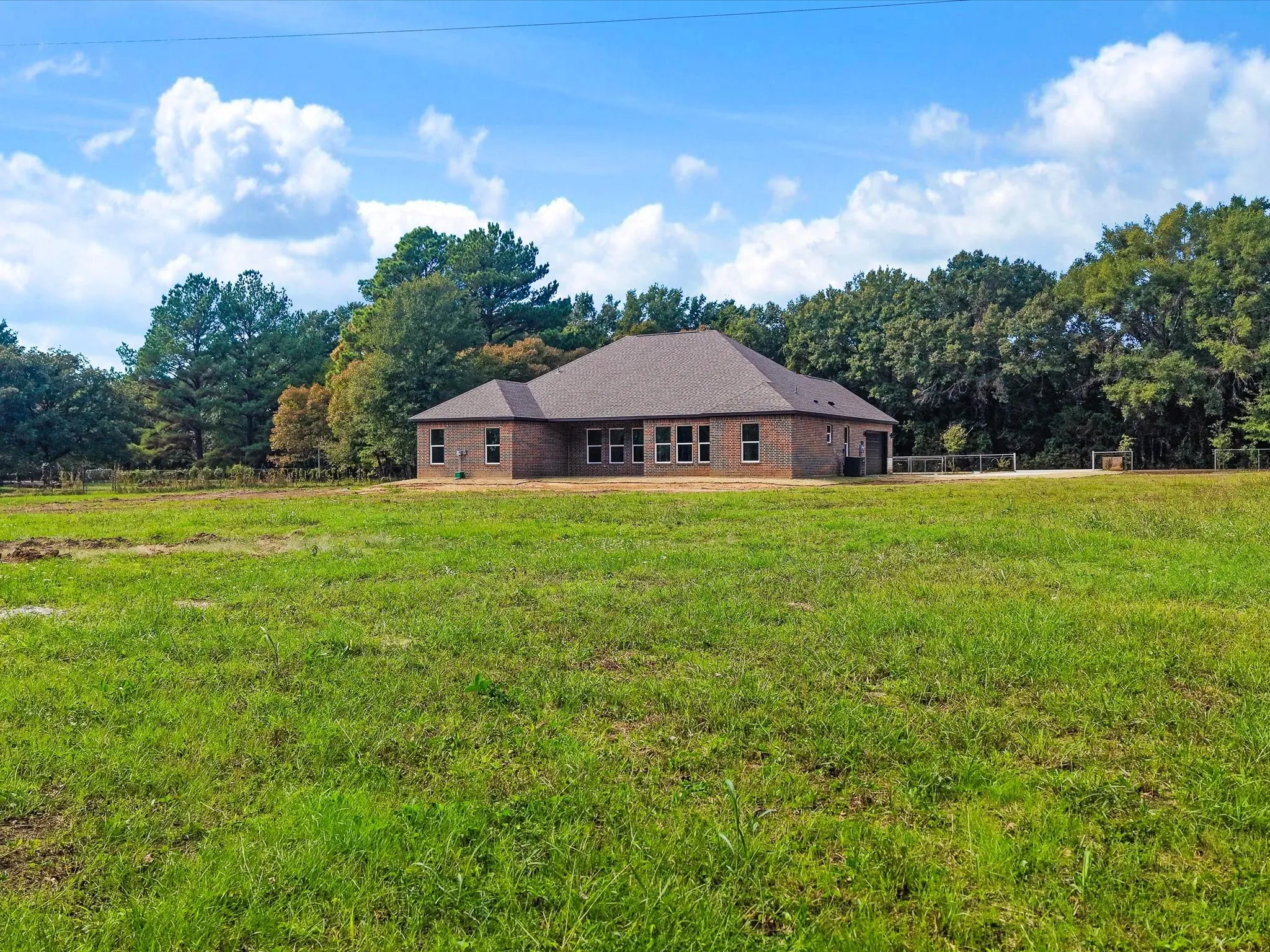 Single-story brick exterior featuring a multi-gabled roofline and expansive surrounding acreage