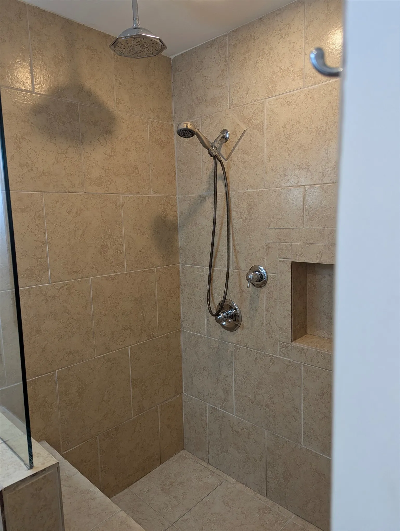 View 2: Tiled walk-in shower with built-in bench, handheld showerhead, and convenient grab bars.