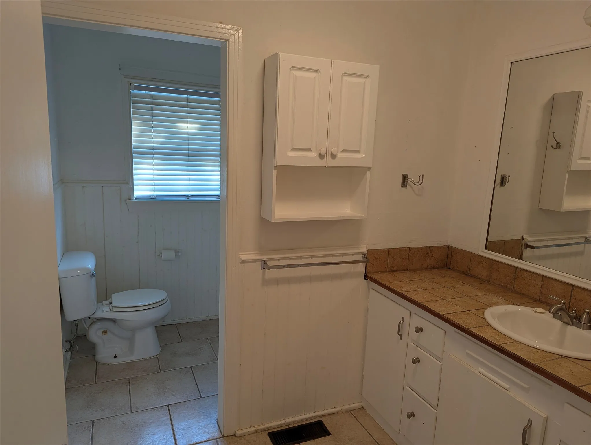 Full bathroom located between Bedrooms #2 and #3, featuring a vanity, built-in cabinetry, and an opportunity for a complete makeover.