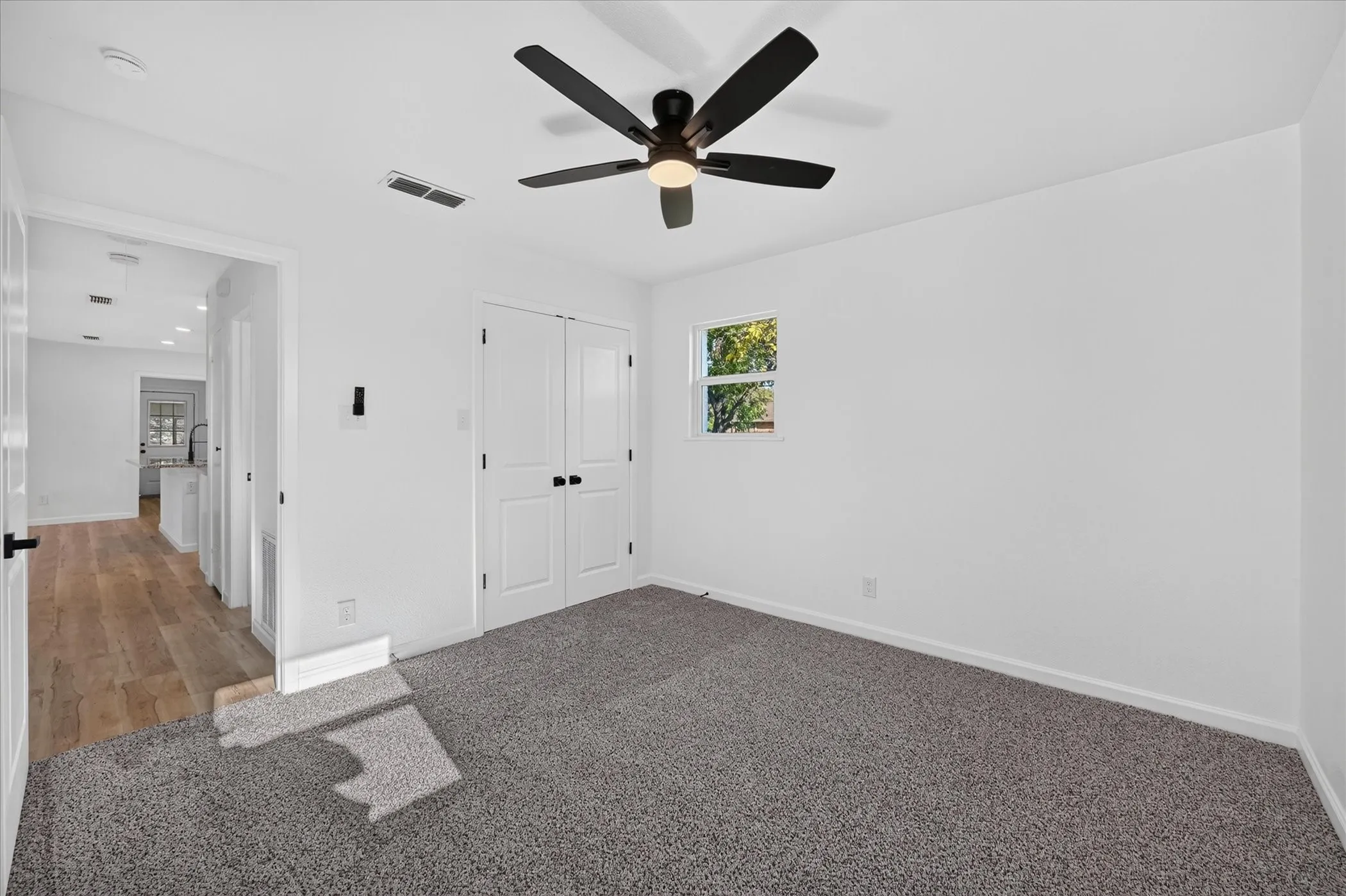 Bedroom featuring neutral carpeting, a dual-door closet, and a matte black ceiling fan with integrated lighting