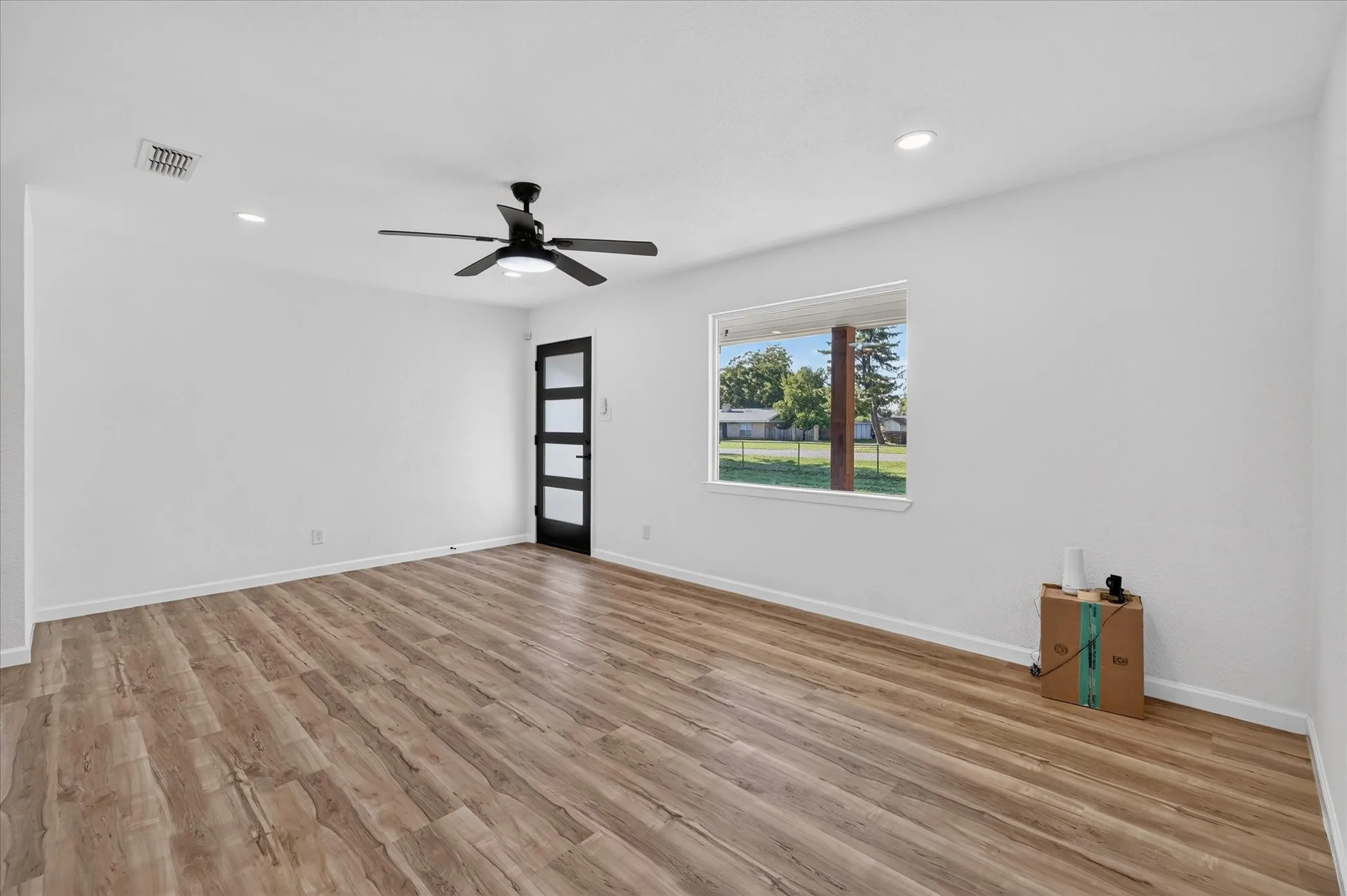 Interior space featuring wood-finish flooring, recessed lighting, a ceiling fan, a multi-pane door, and a rectangular window