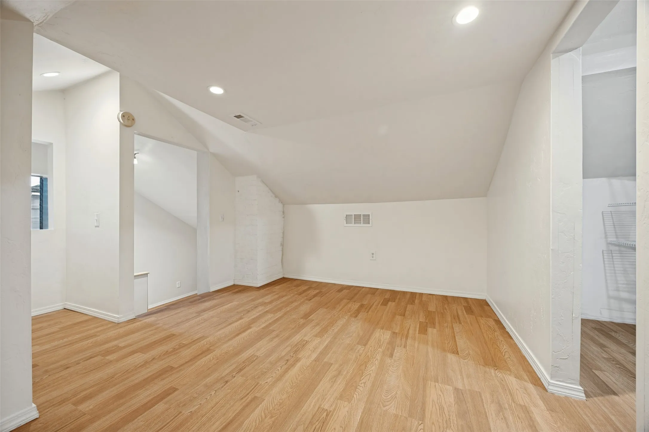 Sloped ceilings featuring recessed lighting and wood-finish flooring
