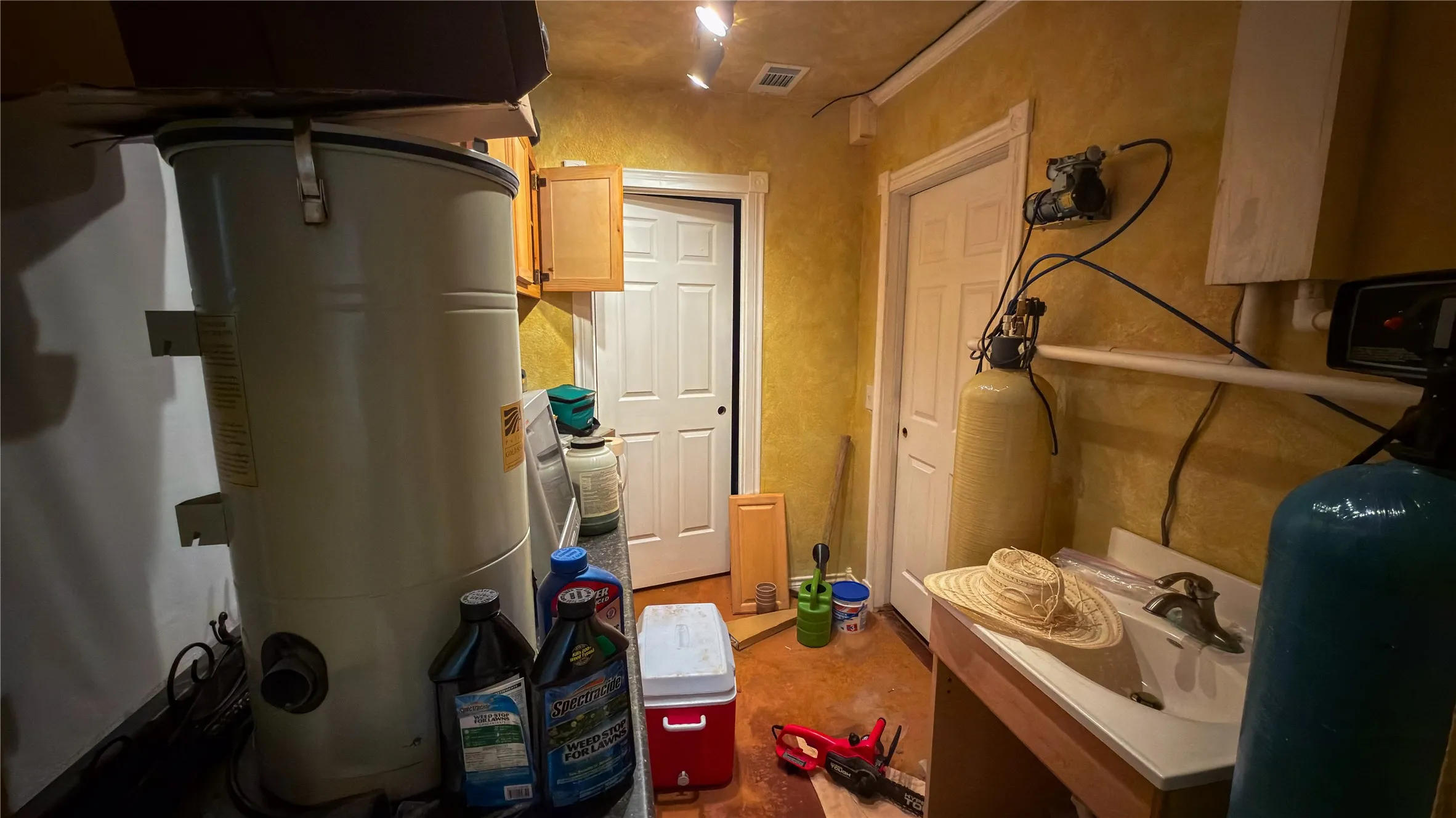 Utility room with integrated water filtration system, cabinetry, and a work sink
