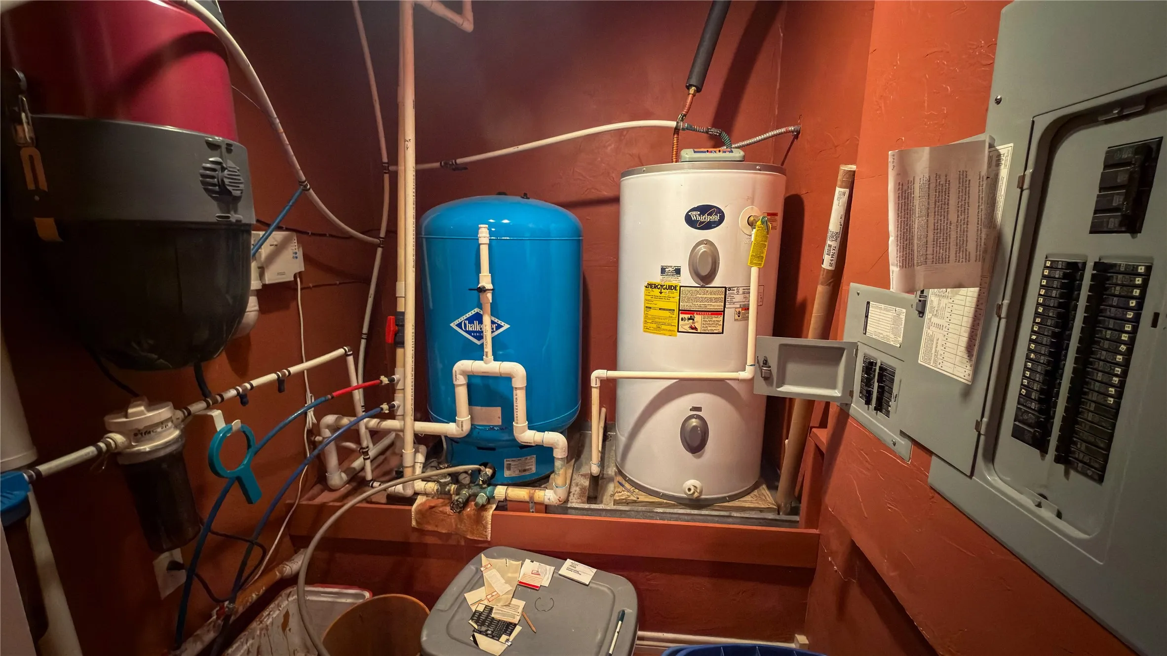 Dedicated utility area featuring a water heater, water filtration system, pressure tank, and electrical panel