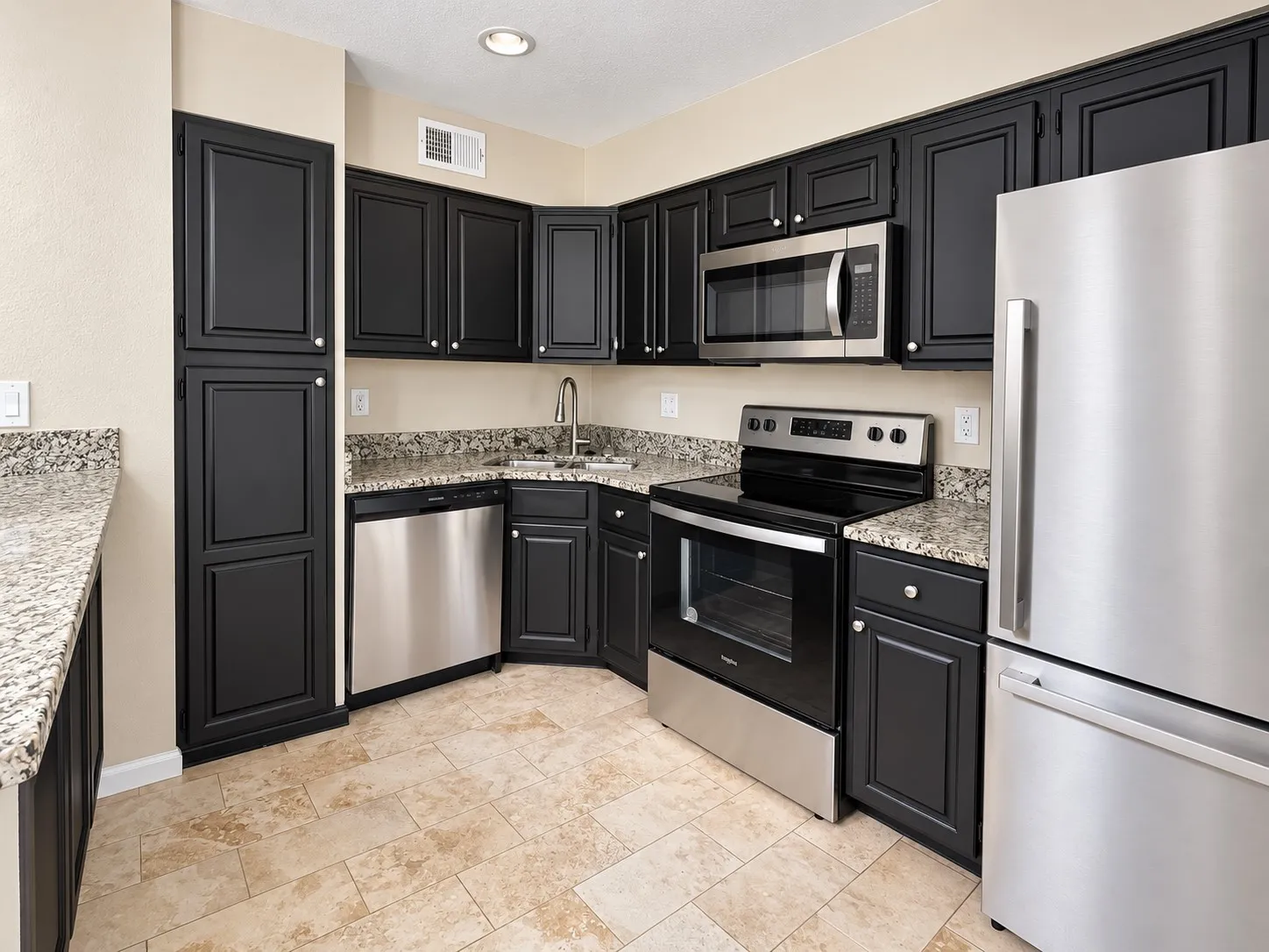 Kitchen featuring black shaker-style cabinetry, stone-finish countertops, stainless steel appliances, and tile flooring
