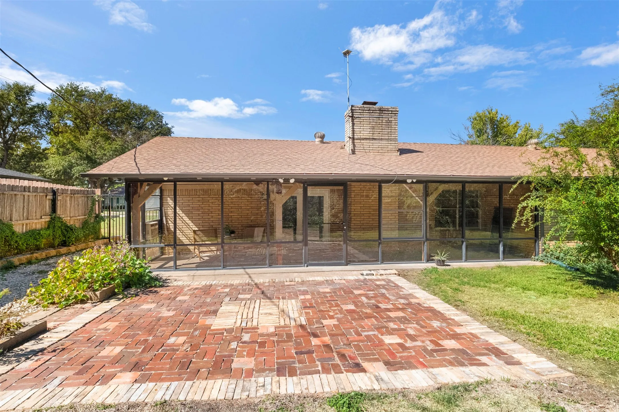 A wide rear view highlights the screened porch, patio, and established backyard landscaping.
