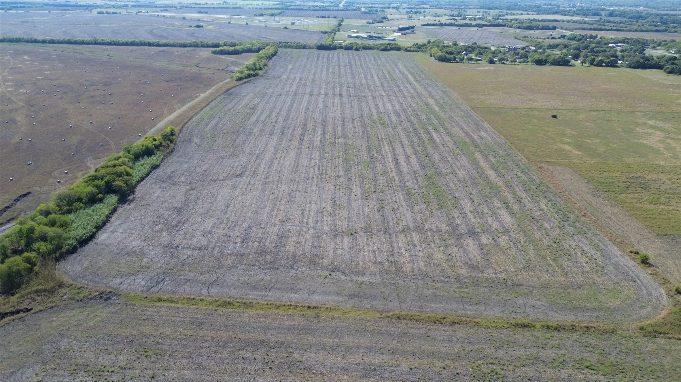 Expansive acreage featuring level topography, cleared open terrain, and mature boundary trees