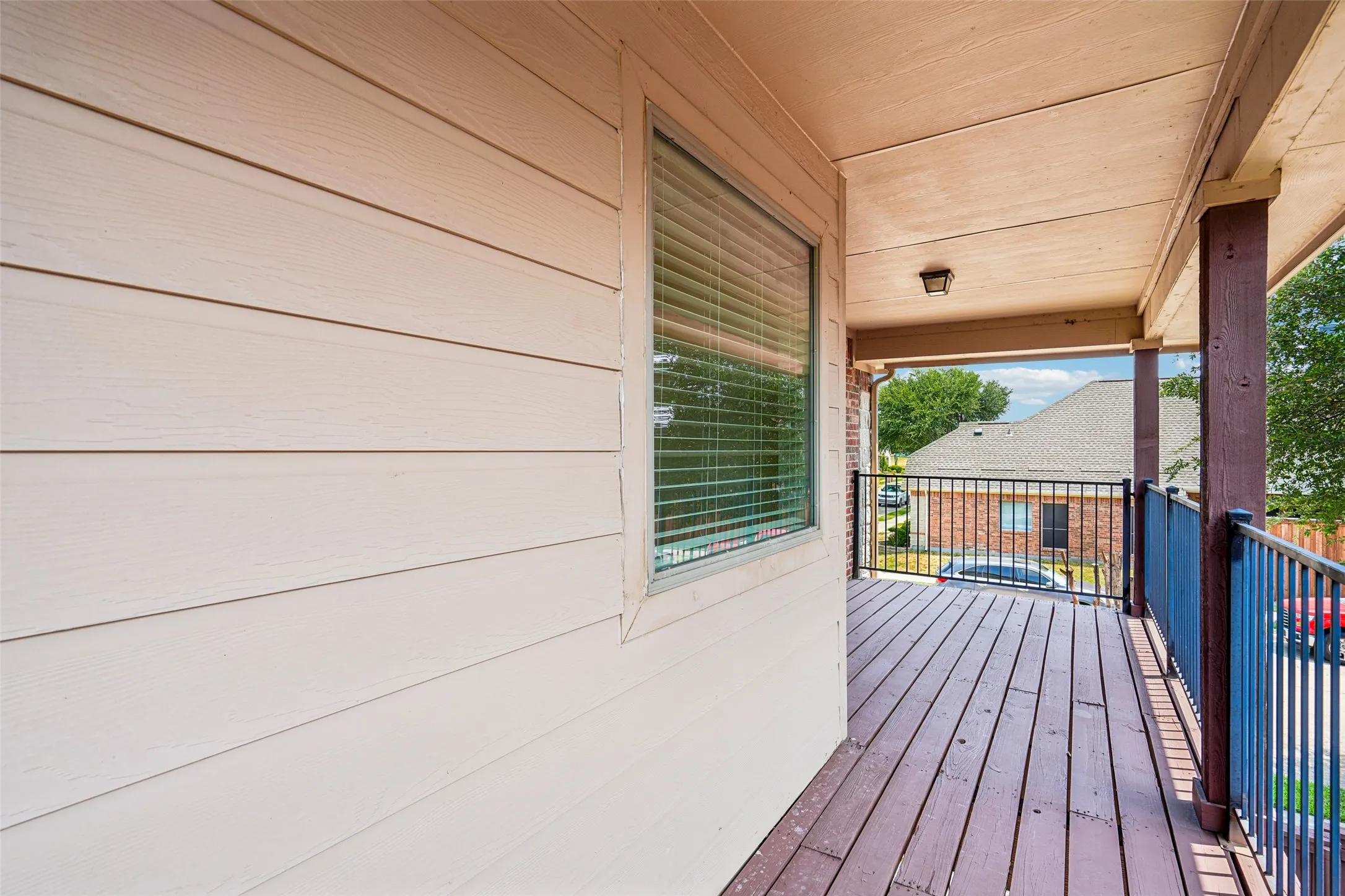 Covered porch featuring horizontal lap siding, wood-plank flooring, and black metal railings