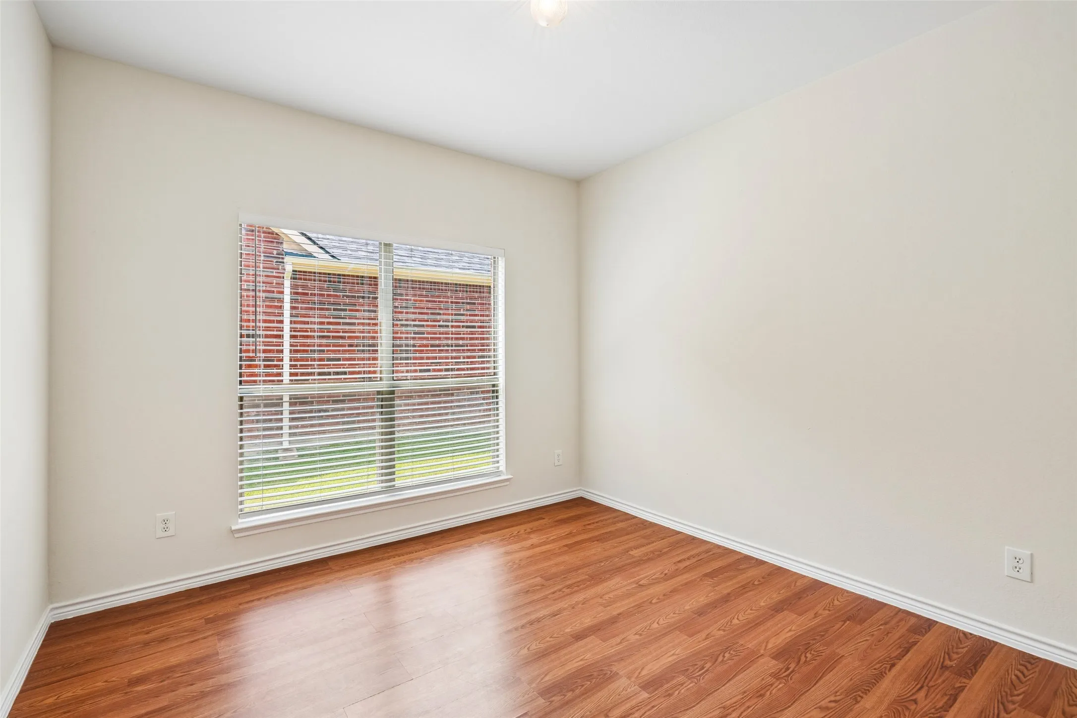 Neutral-toned walls paired with wood-finish flooring and a single-pane window