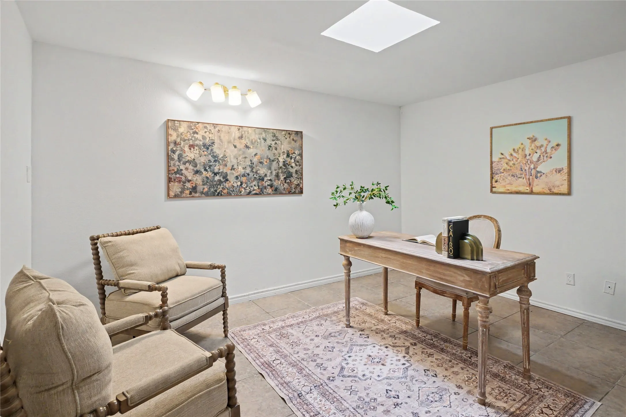 Neutral-toned room featuring light-colored tile flooring, a functional skylight, and wall-mounted multi-bulb lighting