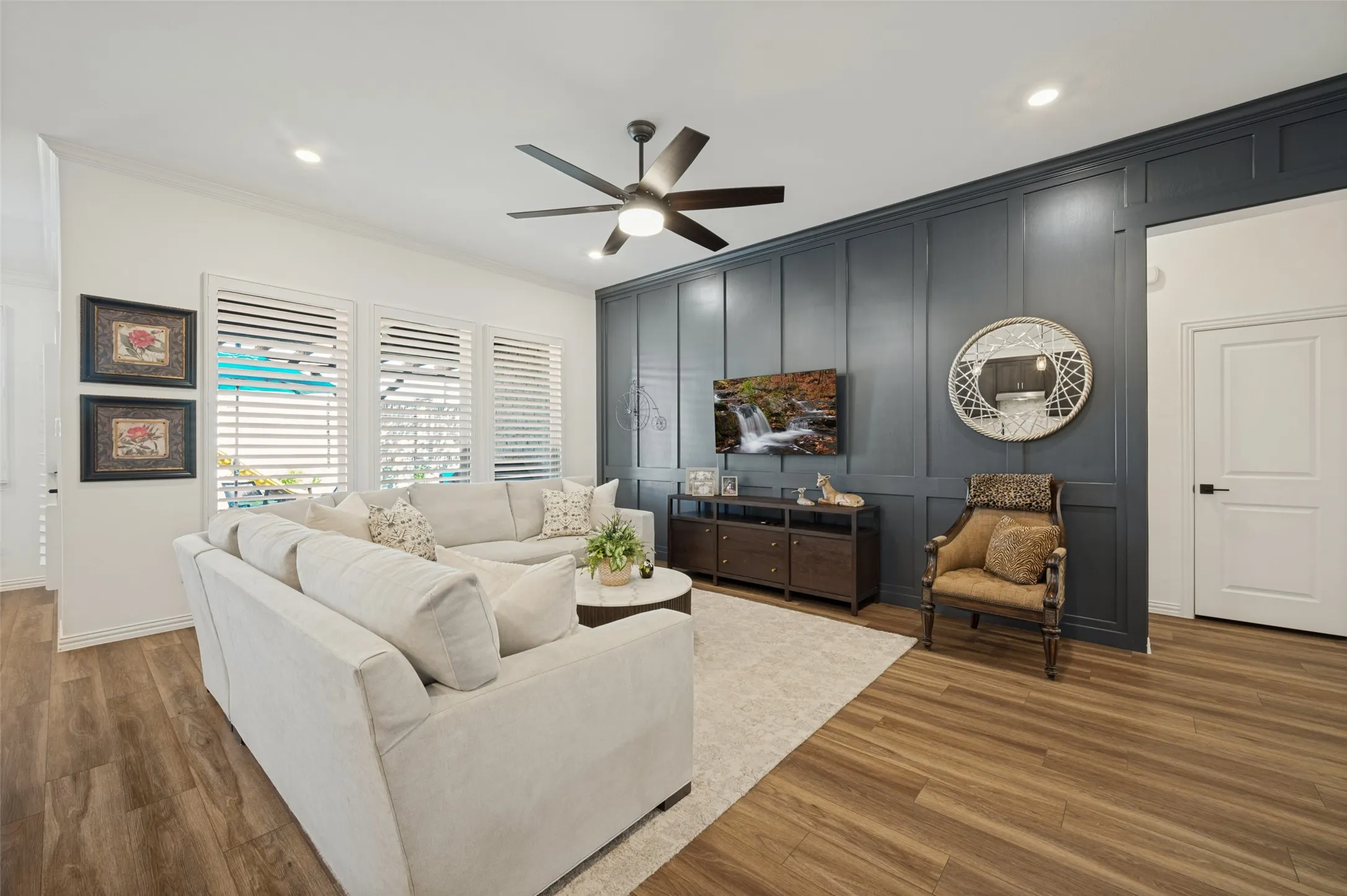 Living area featuring a floor-to-ceiling dark-toned board and batten accent wall, wood-finish flooring, recessed lighting, and a modern multi-blade ceiling fan