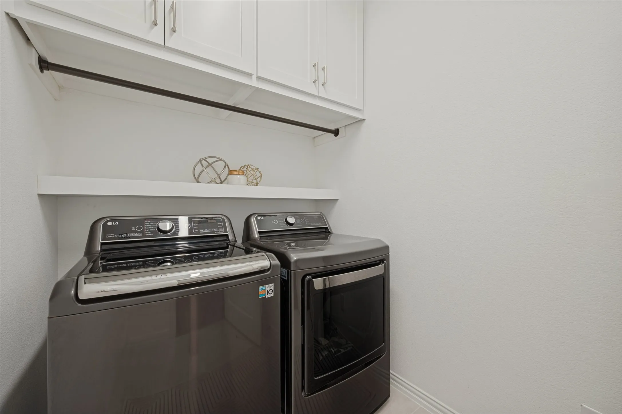 Laundry area featuring white shaker-style wall cabinetry, a mounted garment rod, and an integrated floating shelf