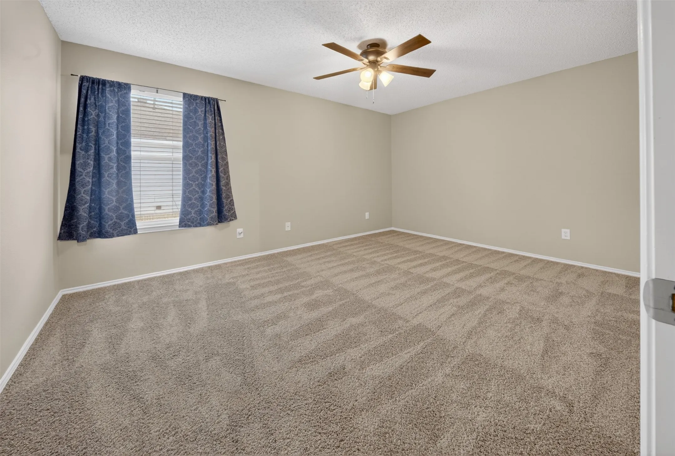 Room featuring neutral wall tones, wall-to-wall carpeting, and a ceiling fan with integrated lighting