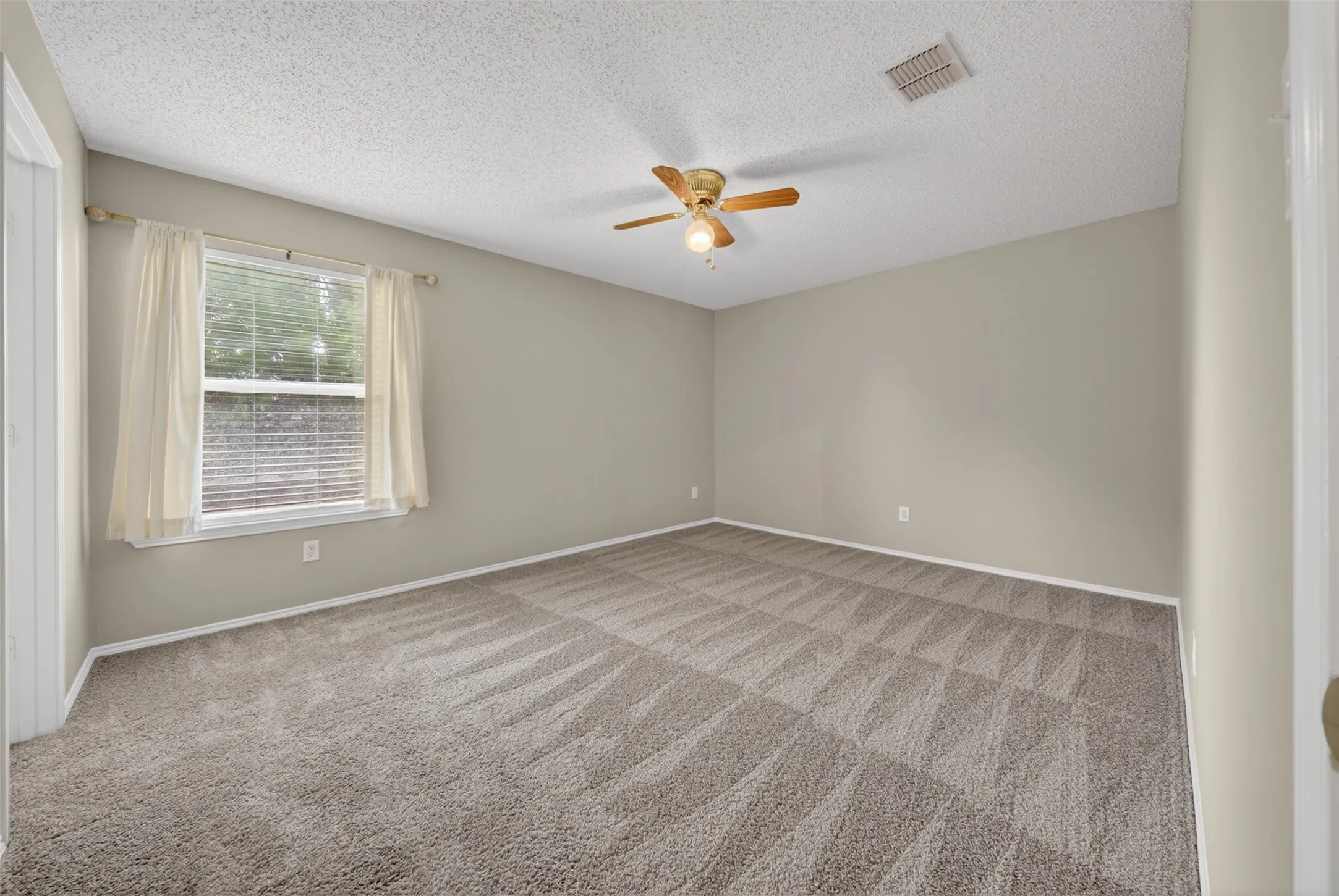 Neutral wall-to-wall carpeting, ceiling fan with light fixture, and windows with horizontal blinds