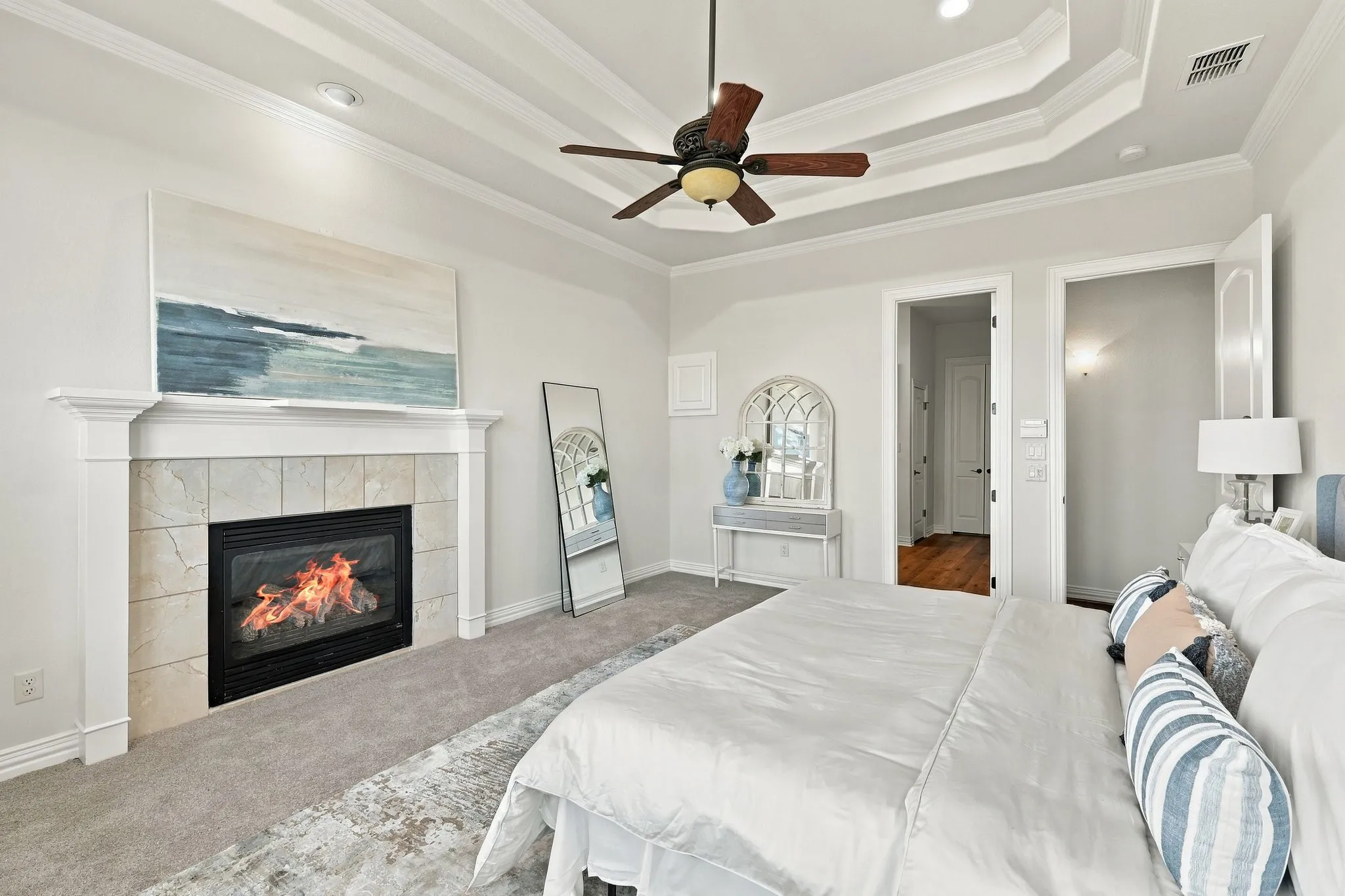 Master suite with coffered ceiling and fireplace with marble-like tile surround