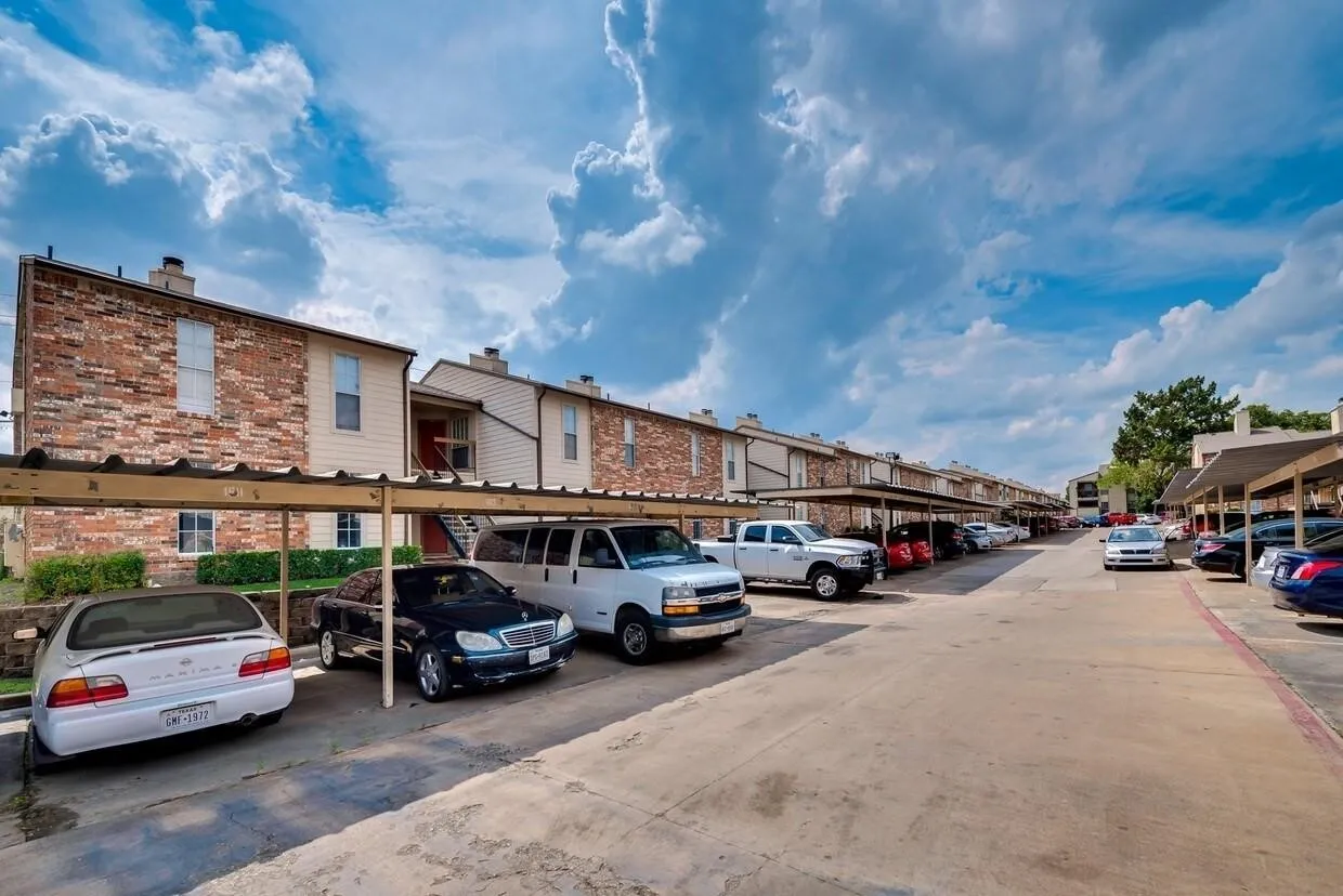 Exterior featuring brick and siding facade with metal-roofed carports