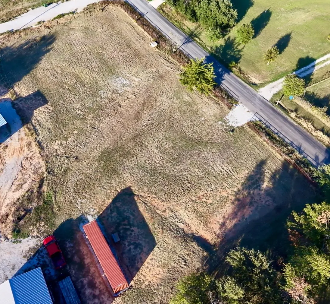 Expansive open lot featuring road frontage, cleared terrain, and mature trees along the perimeter