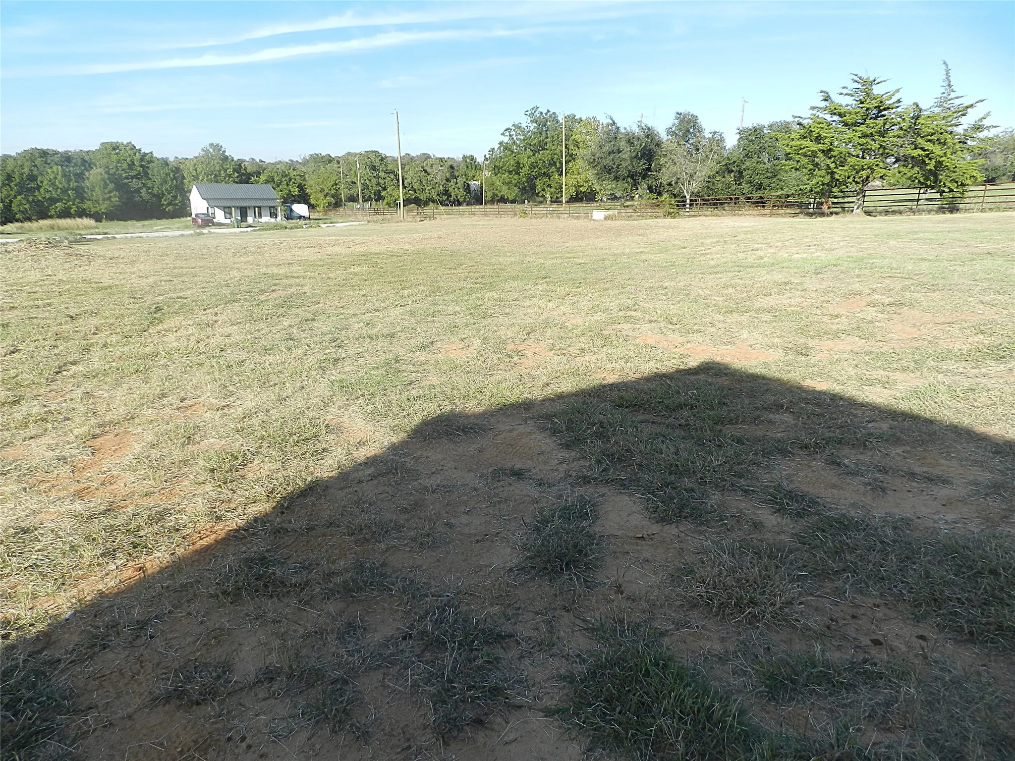 Expansive open acreage featuring native grasses, mature perimeter trees, and post-and-rail fencing
