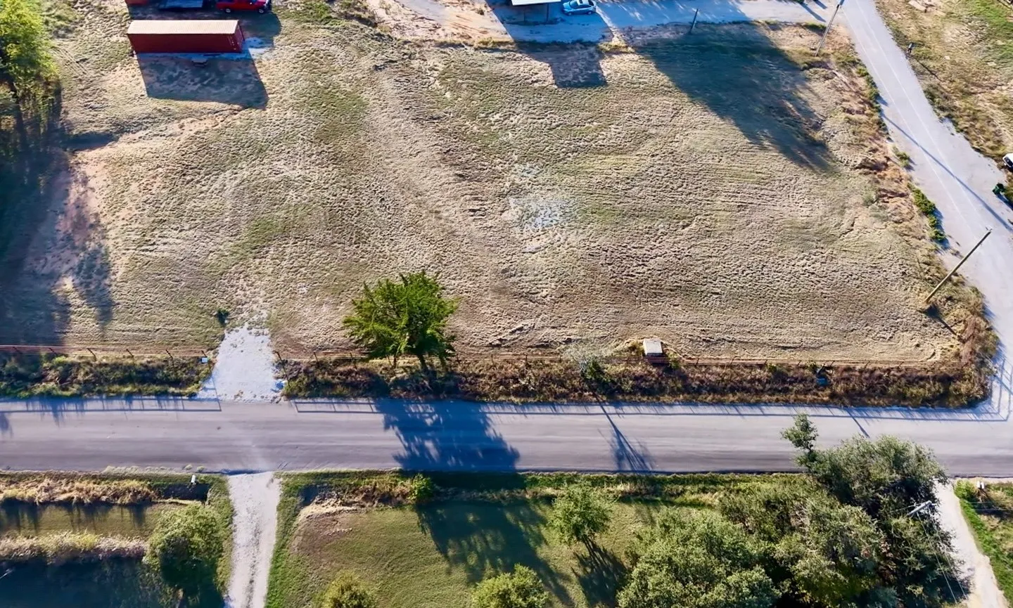 Expansive corner lot featuring open terrain, road frontage, mature trees, and existing perimeter fencing