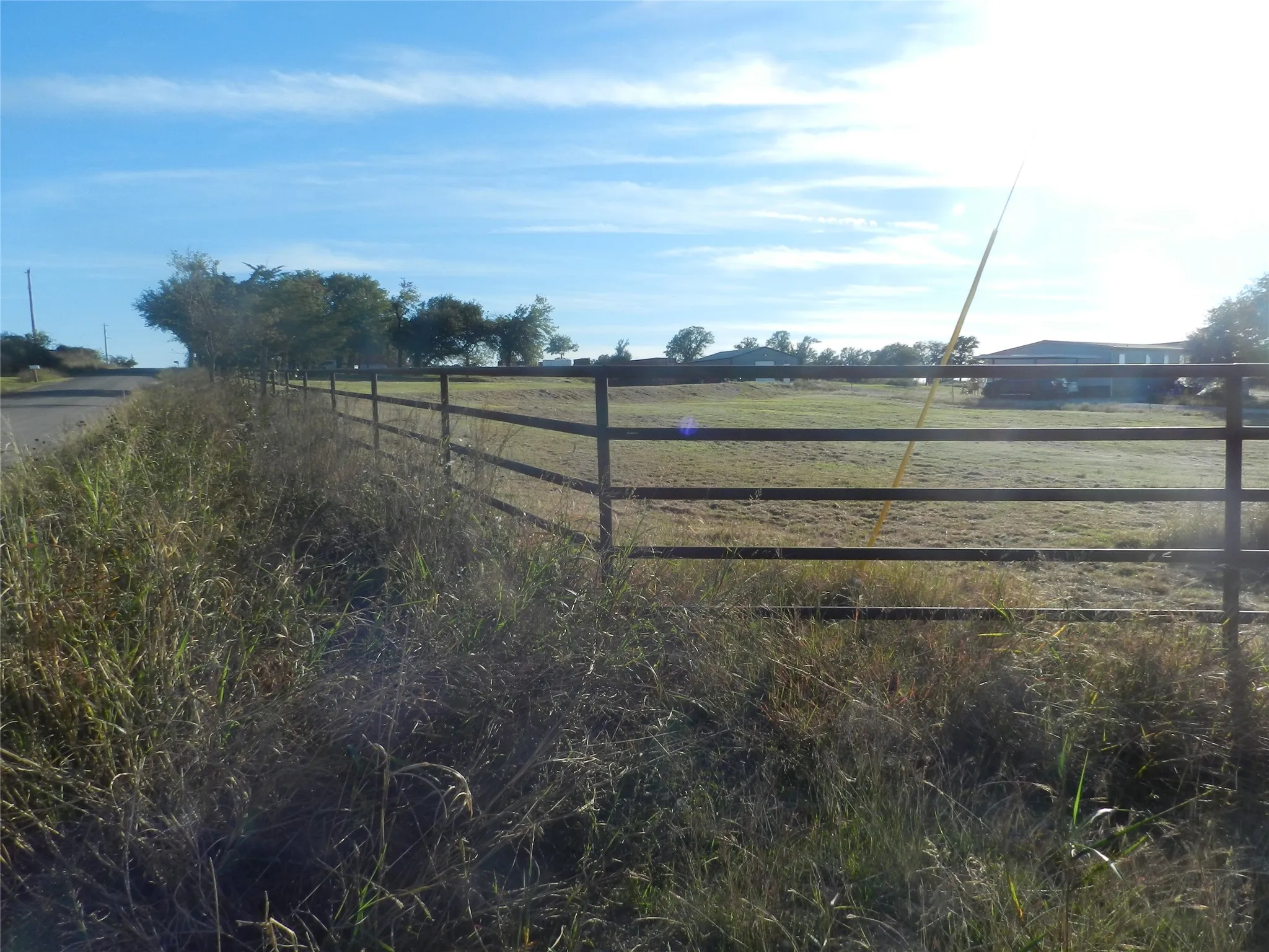 Expansive open acreage enclosed by perimeter metal pipe fencing