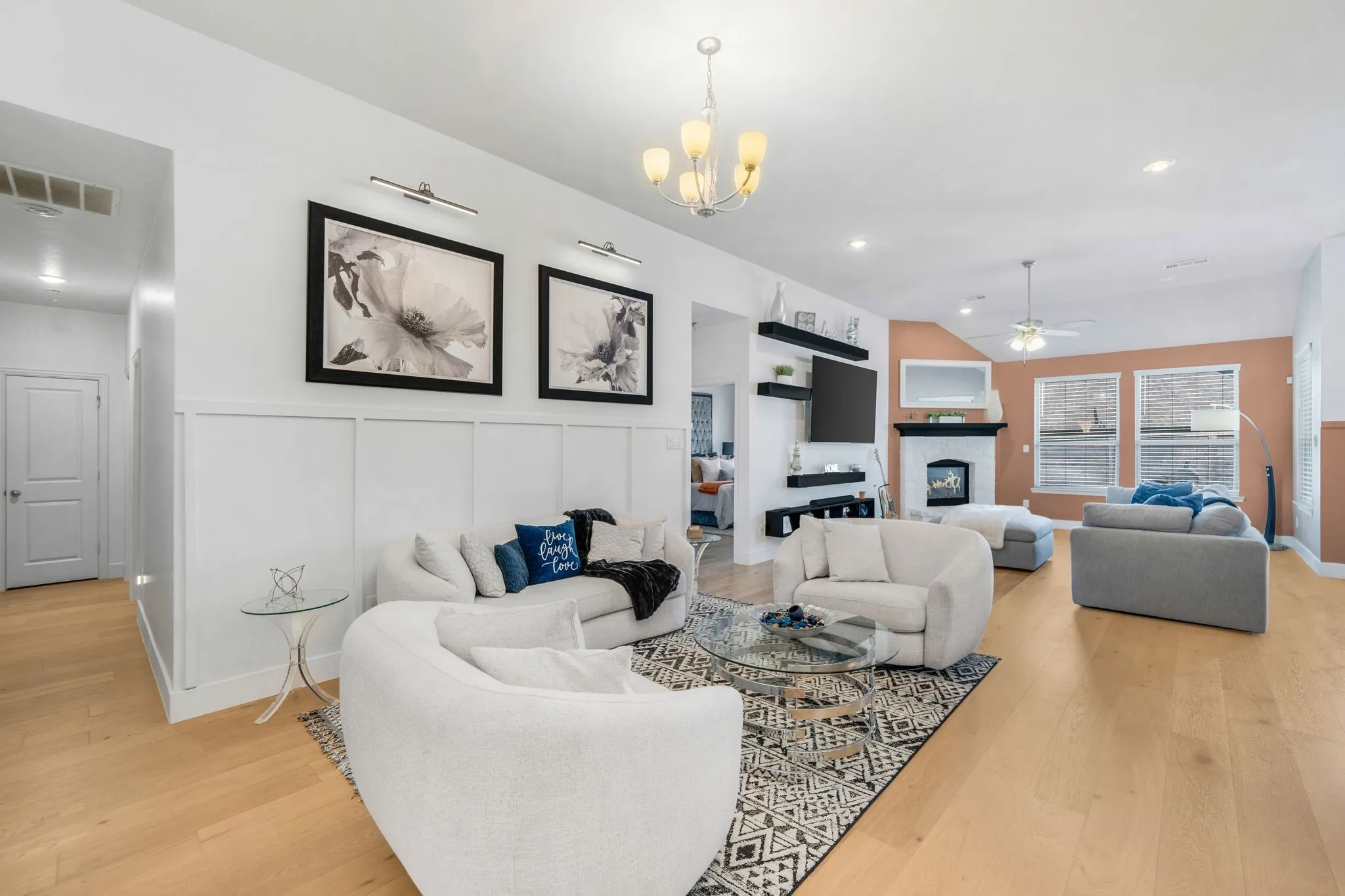 Living area featuring wood-finish flooring, vaulted ceilings, board-and-batten wall detailing, a fireplace with a mantel, and built-in wall shelving