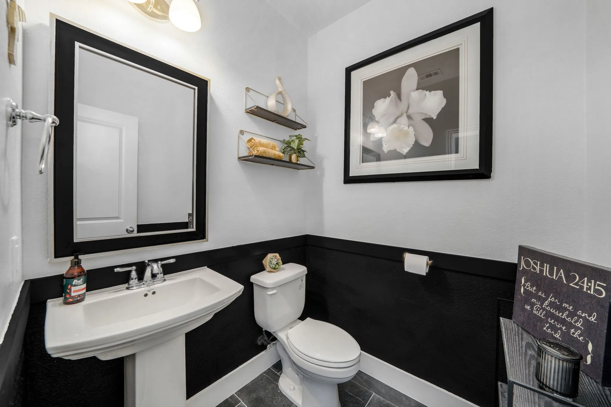 Pedestal sink with chrome dual-handle faucet, framed wall mirror, and dual-tone wall finish featuring horizontal trim detailing and tile flooring